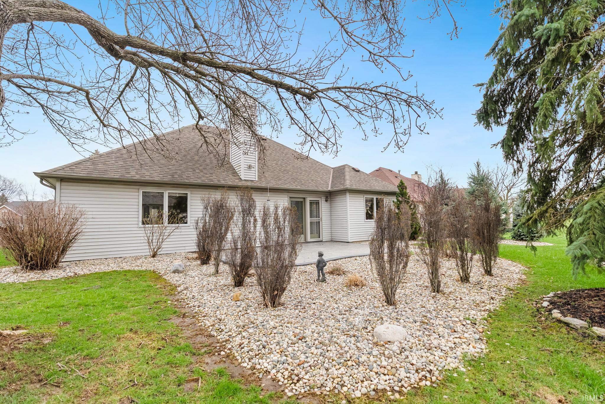 Rear view of property with a patio, a lawn, roof with shingles, and a chimney