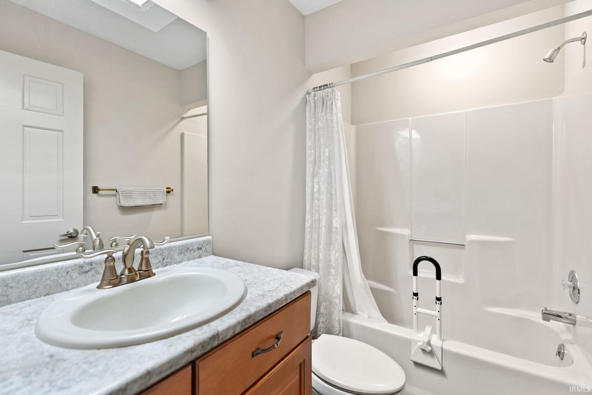 Bathroom featuring vanity, shower / tub combo with curtain, and a skylight