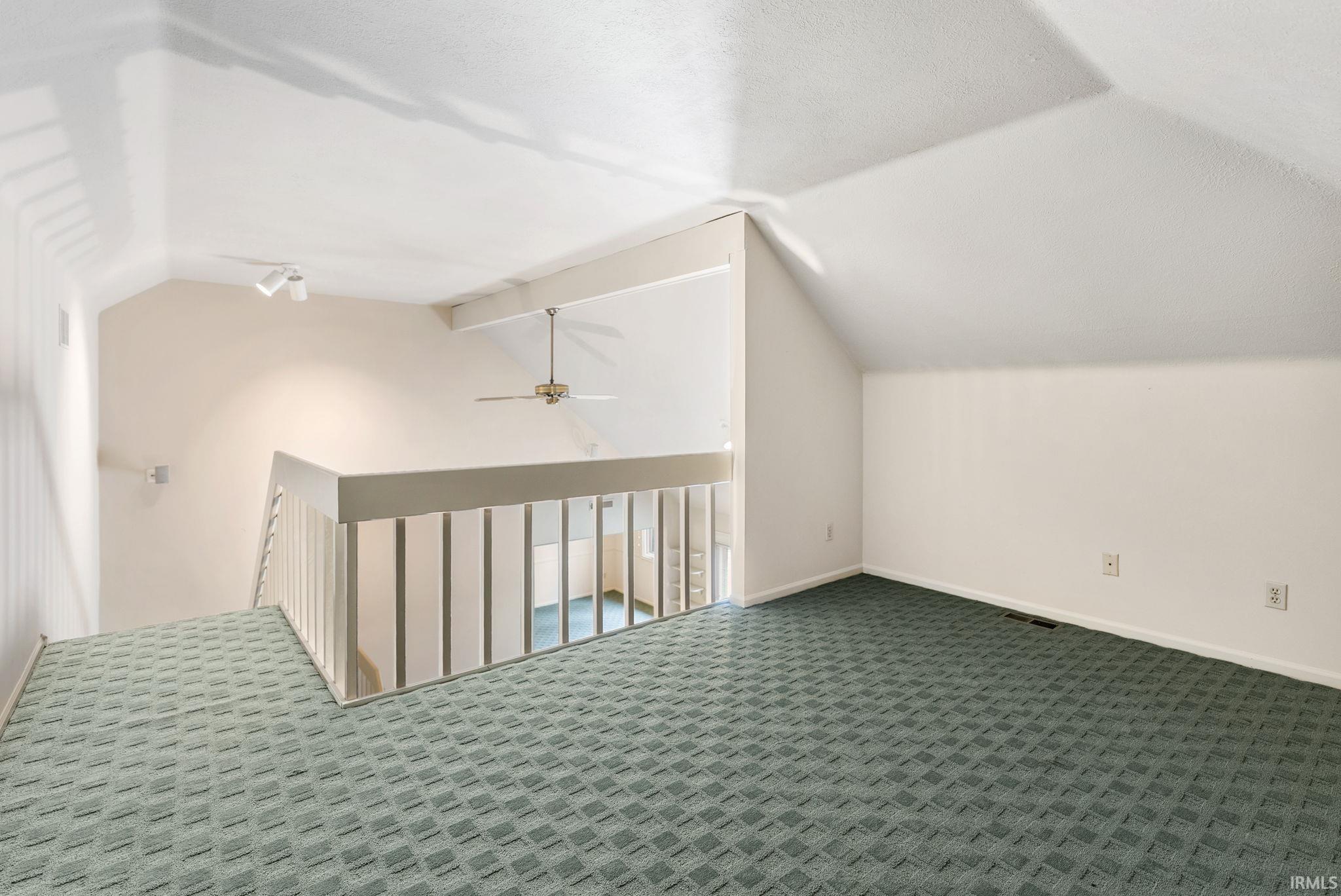 Bonus room with a ceiling fan and dark colored carpet