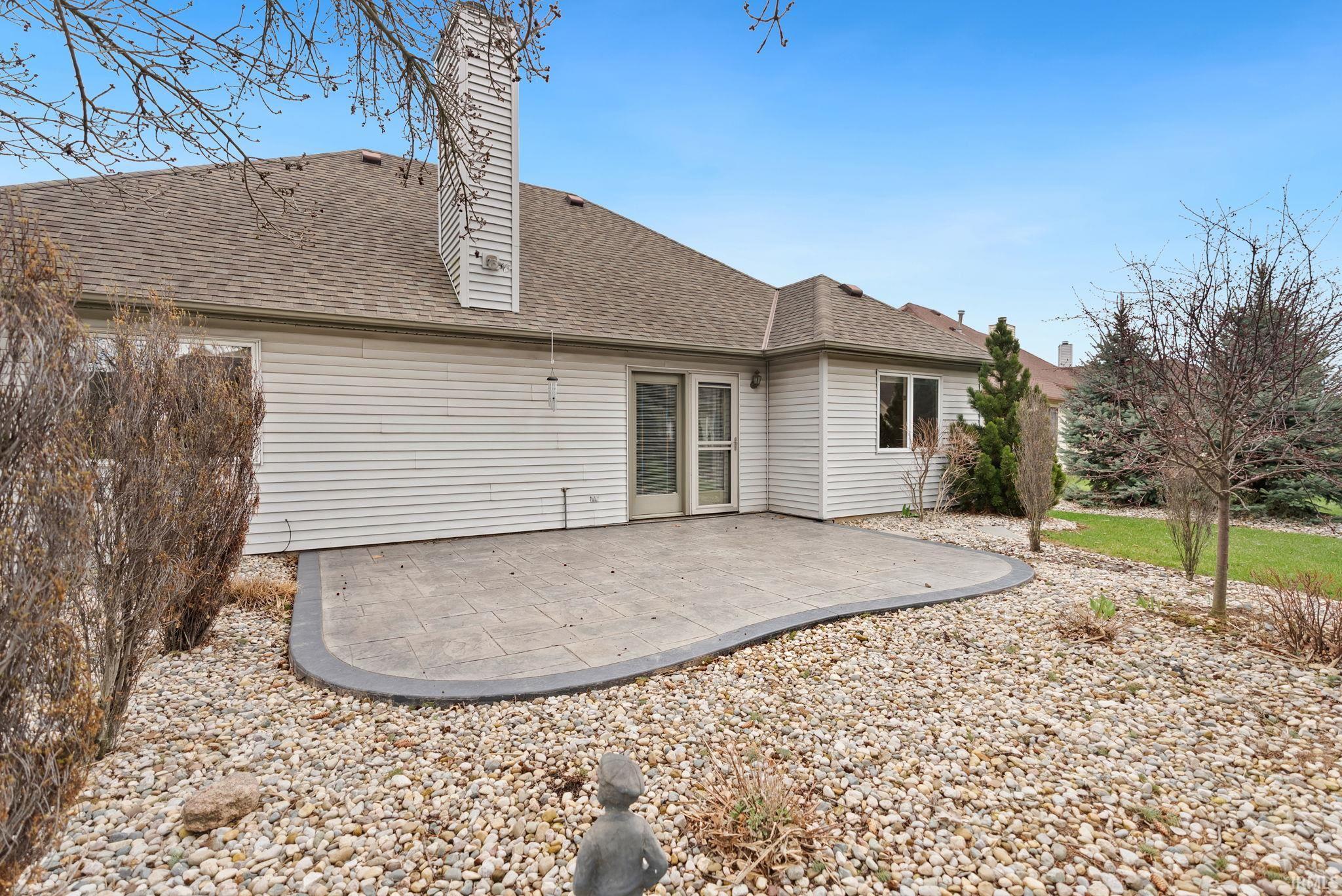 Rear view of house with a patio, a chimney, and a shingled roof
