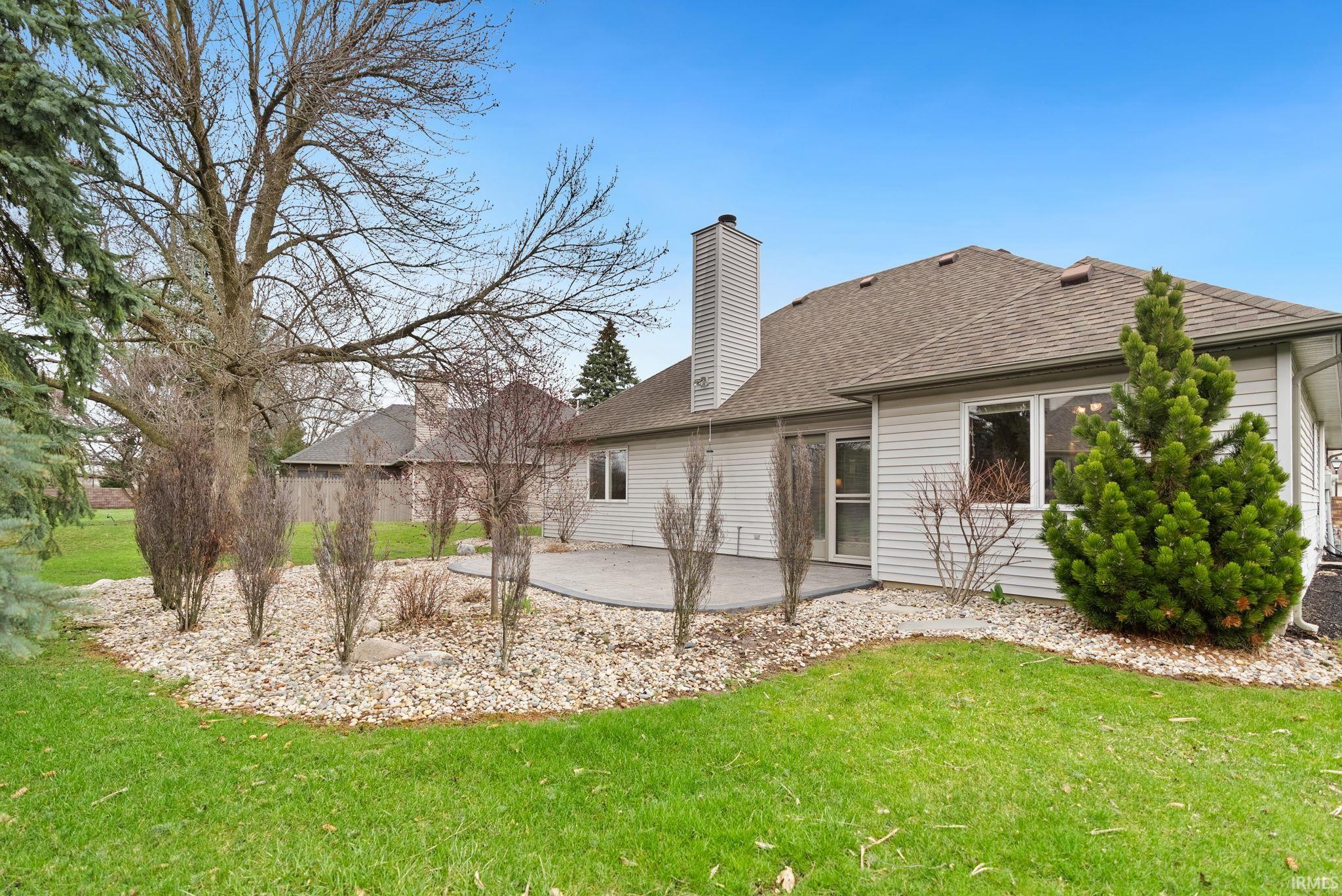 Rear view of property with a patio, a yard, a chimney, and a shingled roof