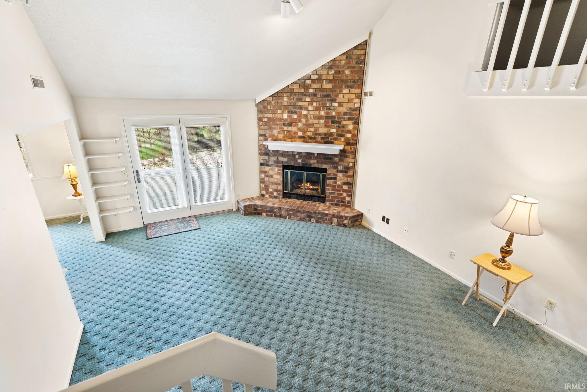 Unfurnished living room featuring vaulted ceiling, a fireplace, and carpet floors
