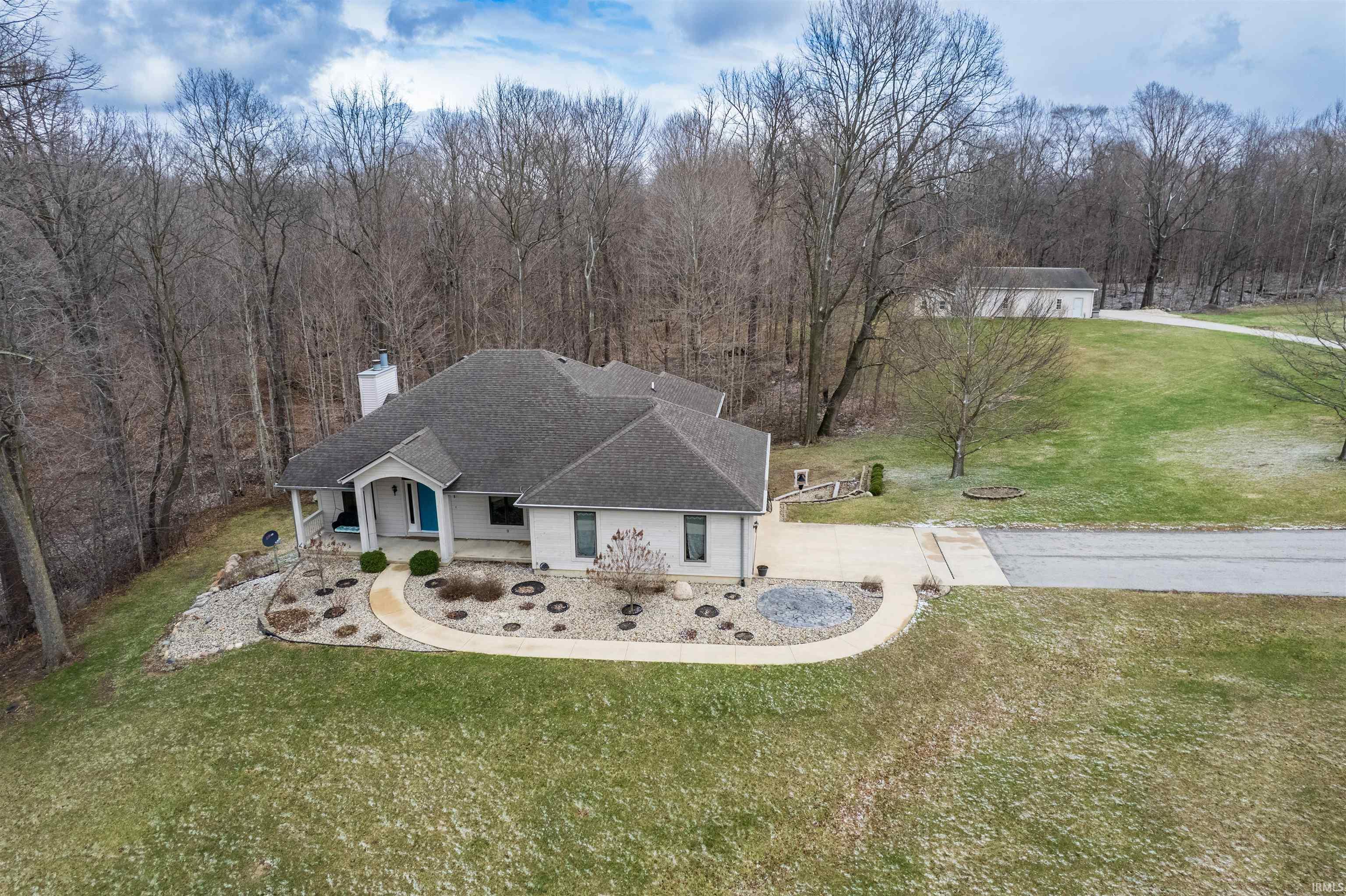 View of front of home with a front yard, roof with shingles, covered porch, and a chimney