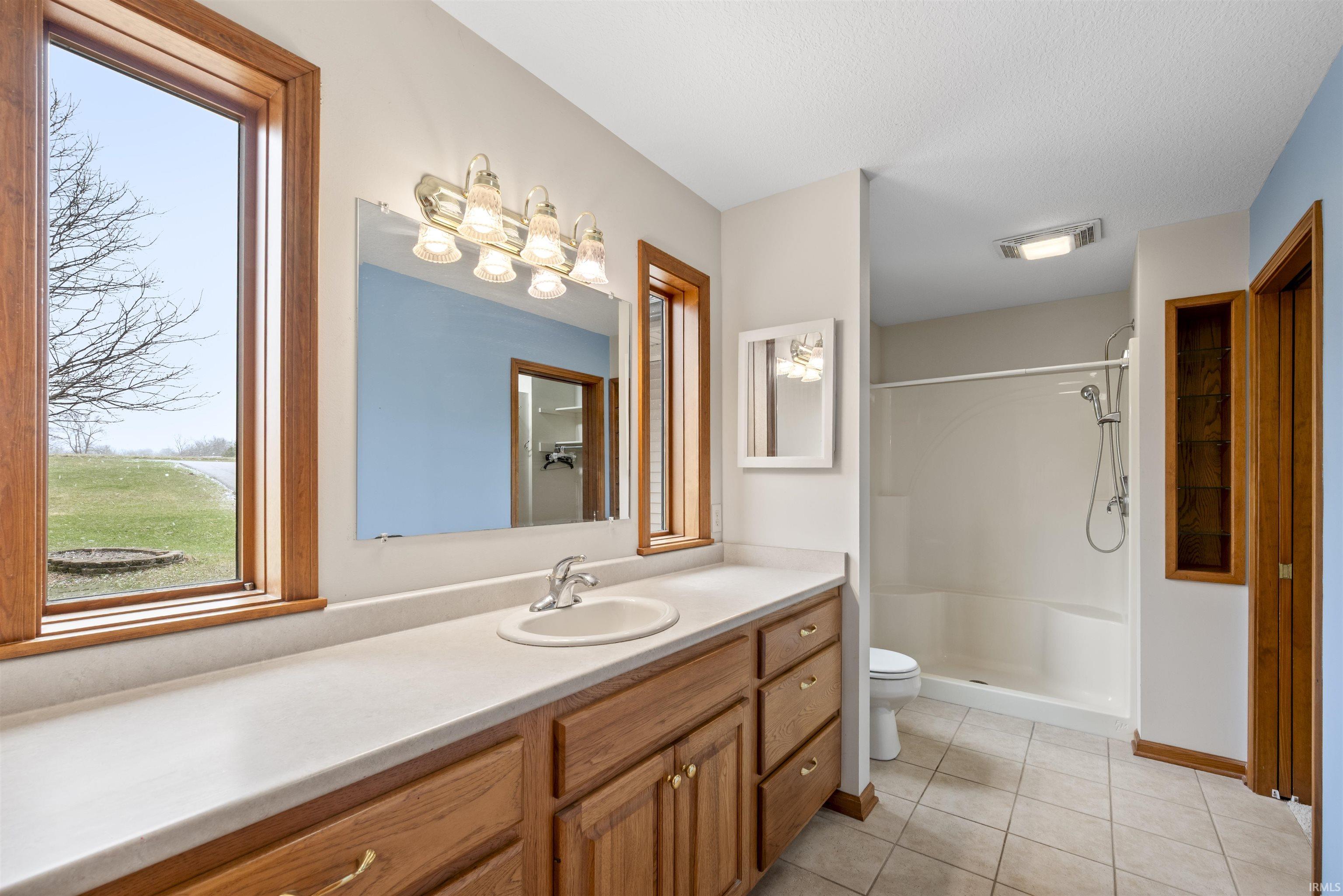 Full bathroom with vanity, a stall shower, and light tile patterned flooring