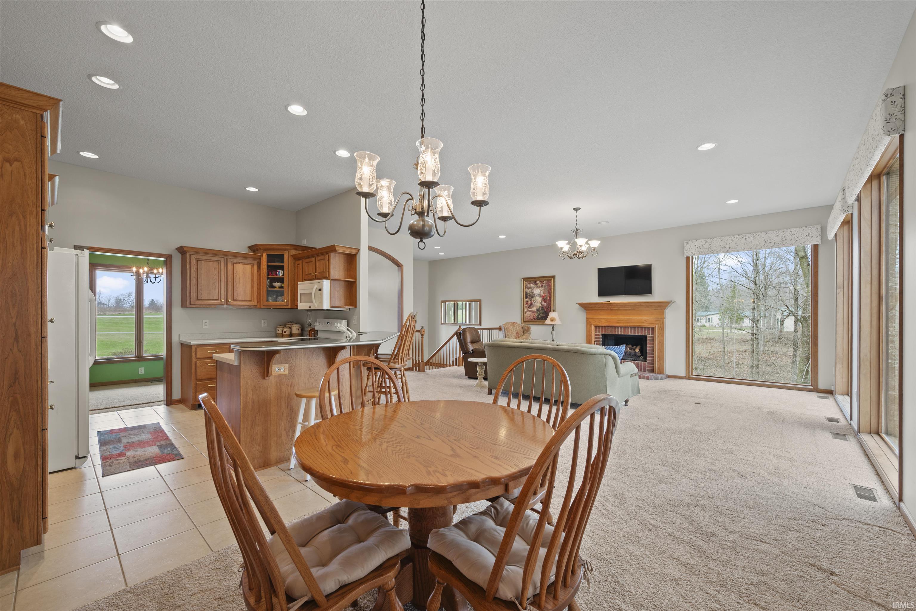 Dining space with hanging lights, a fireplace, and light colored carpet