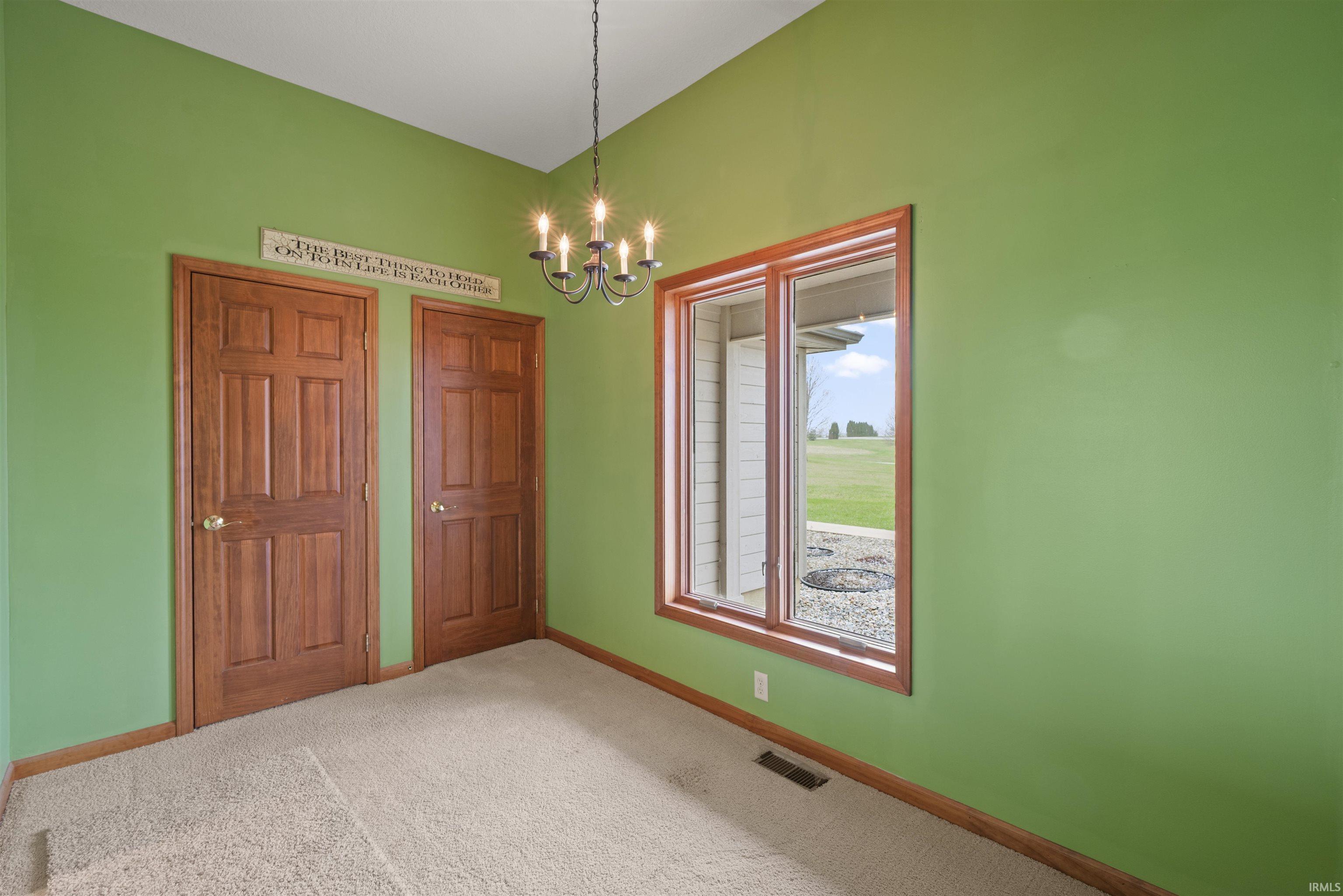 Unfurnished bedroom with two closets, light colored carpet, and a chandelier