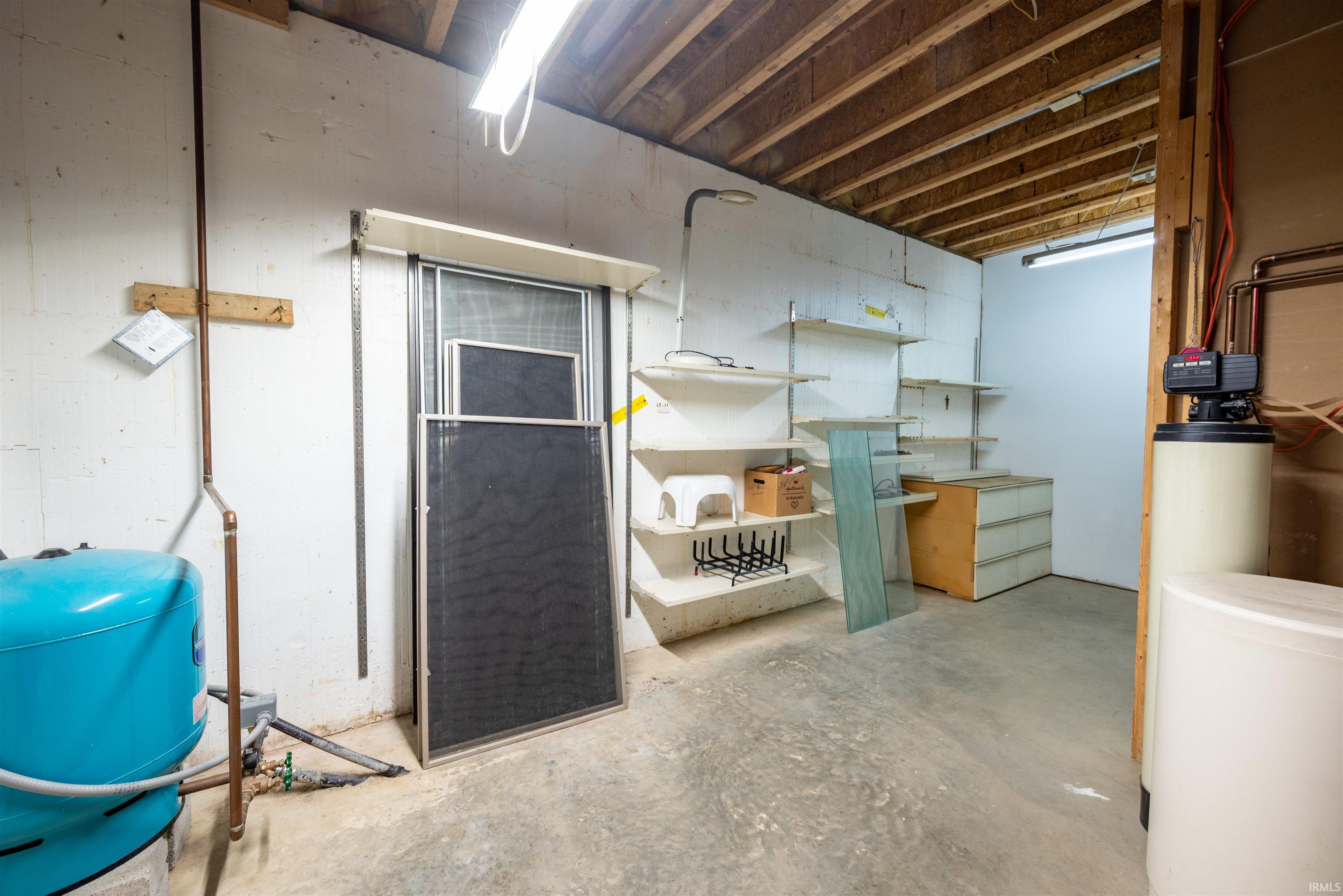 Unfinished basement with a water pressure tank and a water softener