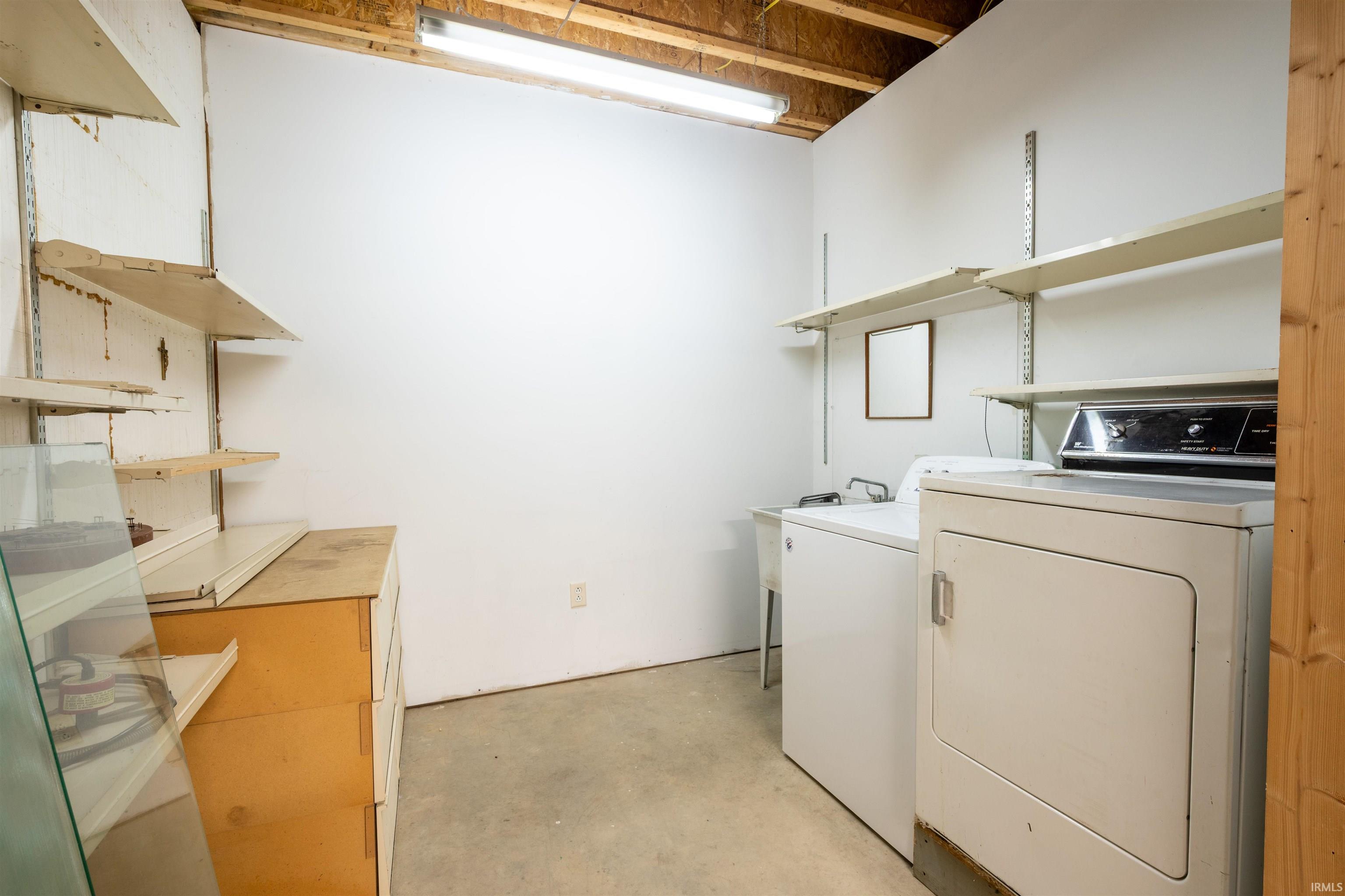 Laundry area featuring concrete flooring and washing machine and clothes dryer