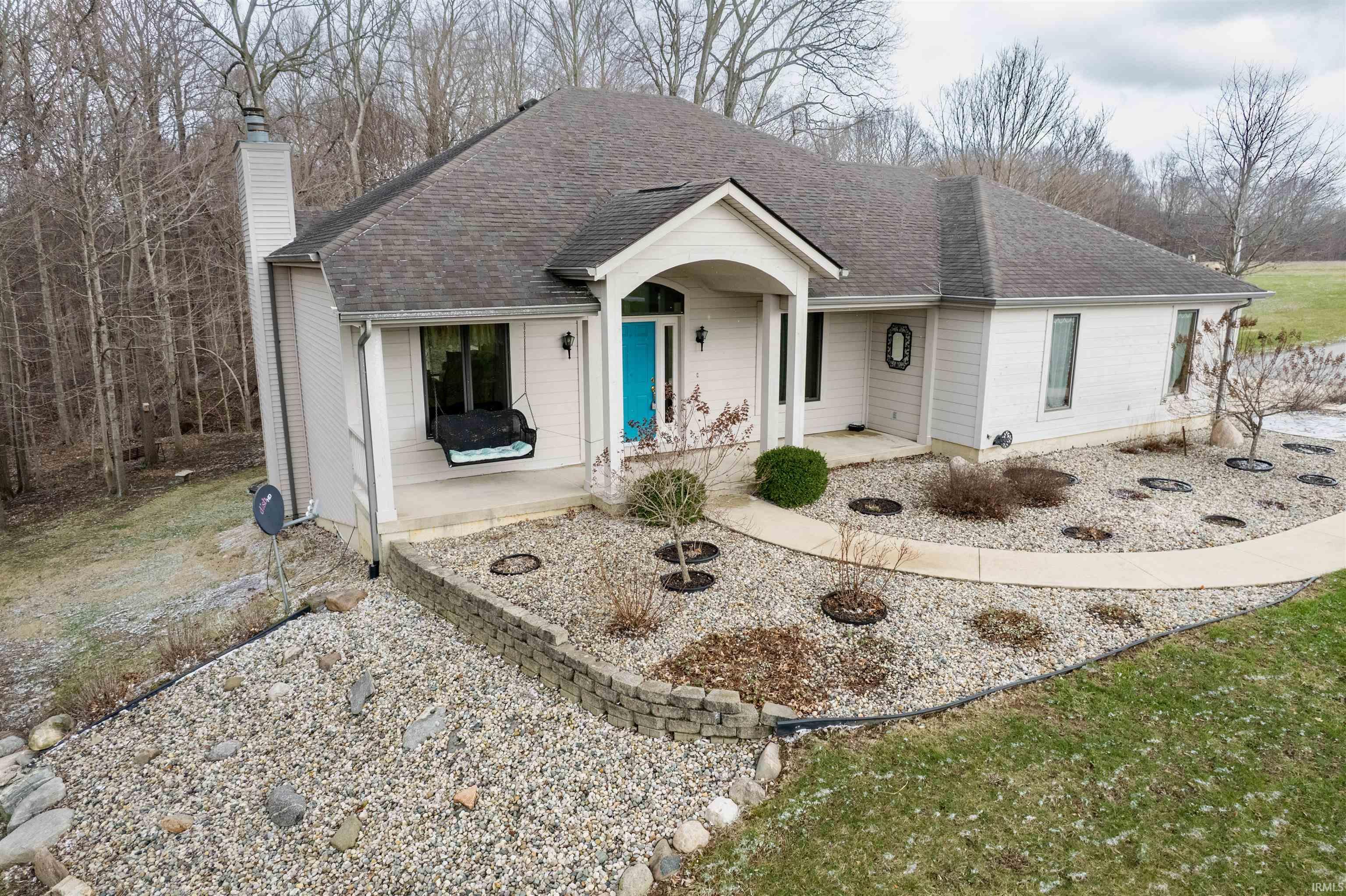 Ranch-style home with roof with shingles, a chimney, and a porch