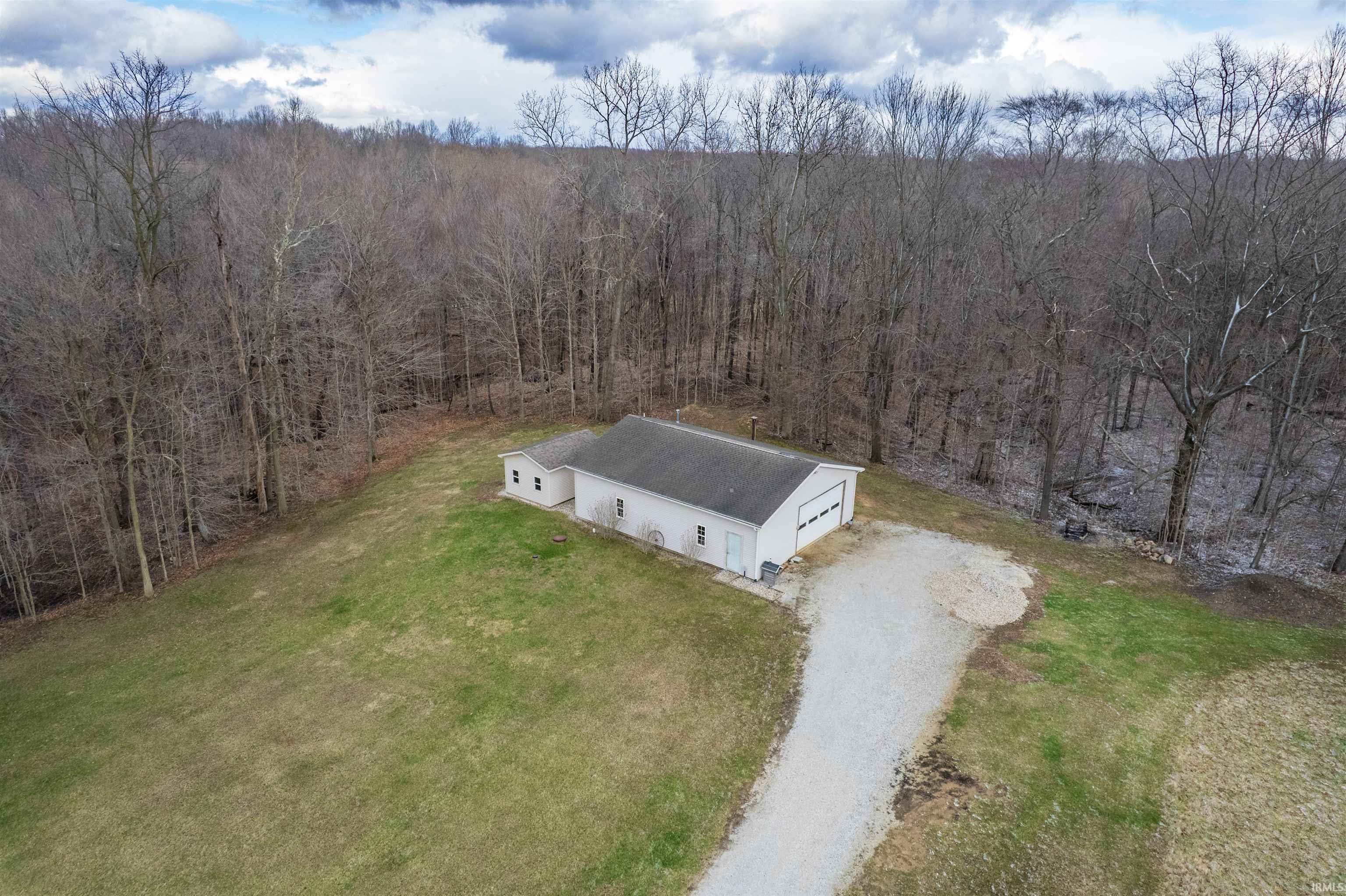 Aerial view of property and surrounding area featuring a heavily wooded area