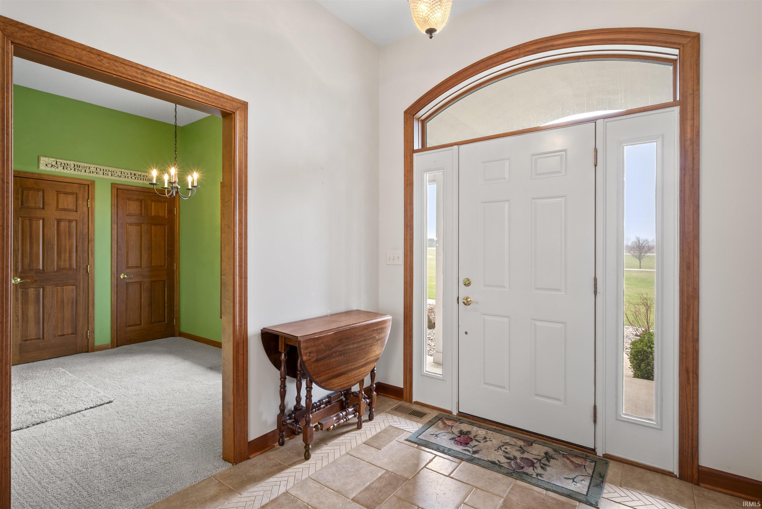 Entryway with a chandelier, healthy amount of natural light, and light carpet