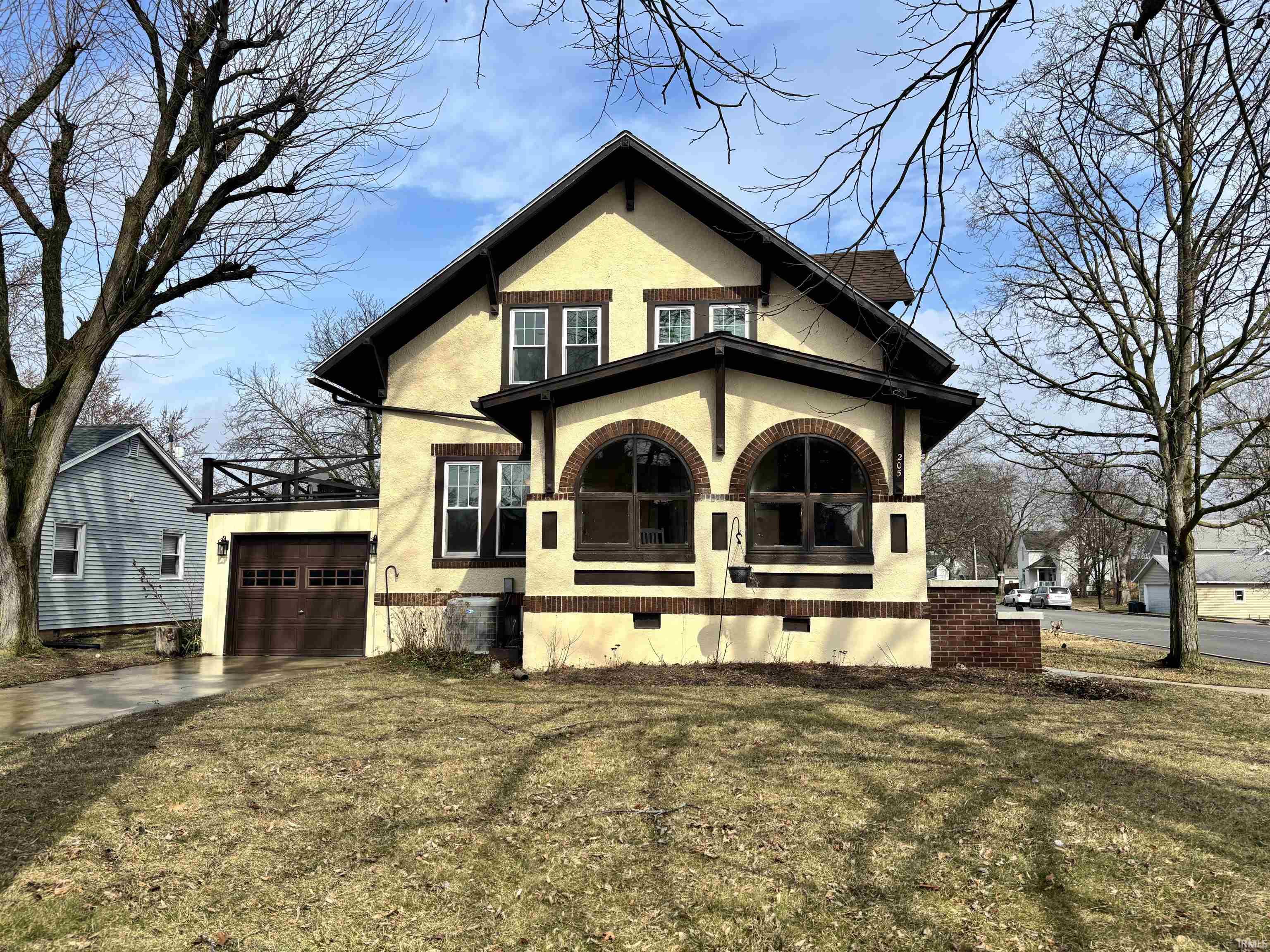View of front of house with stucco siding, covered porch, a front yard, driveway, and a garage