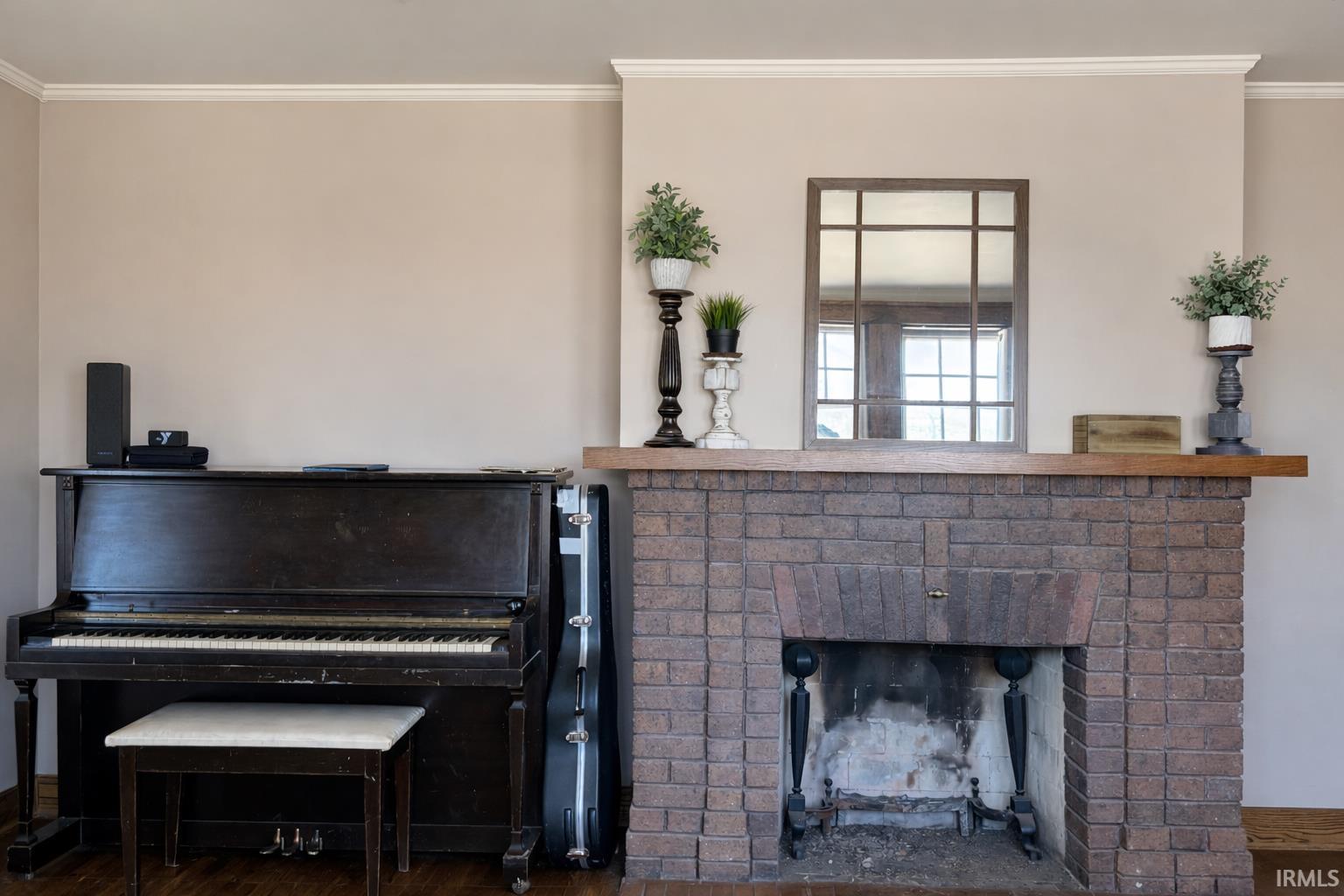 Detailed view of ornamental molding, a brick fireplace, and wood finished floors