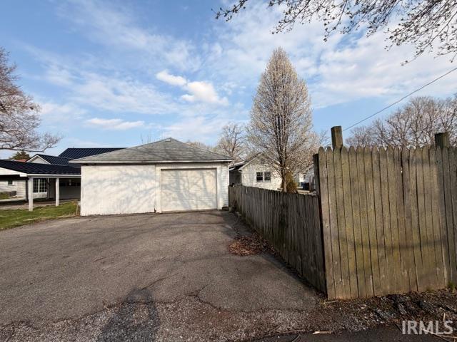 View of property exterior with an outdoor structure, a detached garage, and driveway