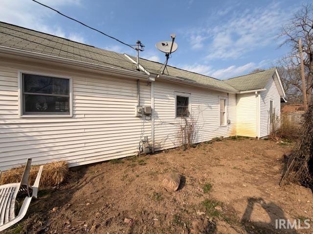 View of side of home with roof with shingles