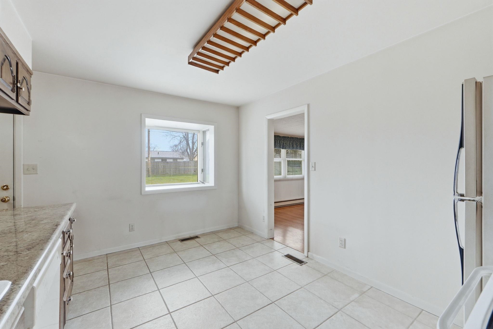 Kitchen with white appliances, light countertops, light tile patterned floors, and a baseboard radiator
