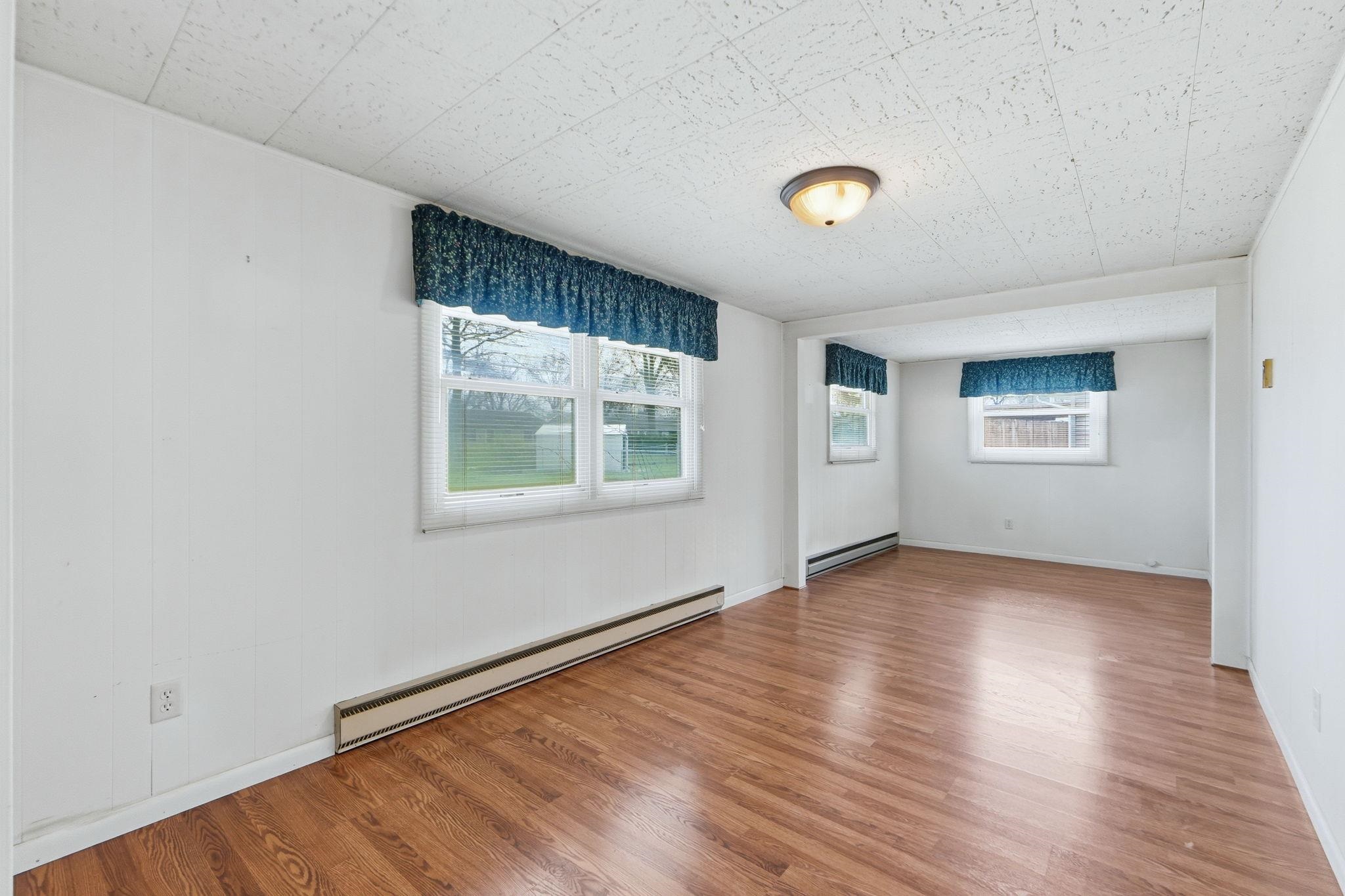 Unfurnished room featuring baseboard heating and wood finished floors