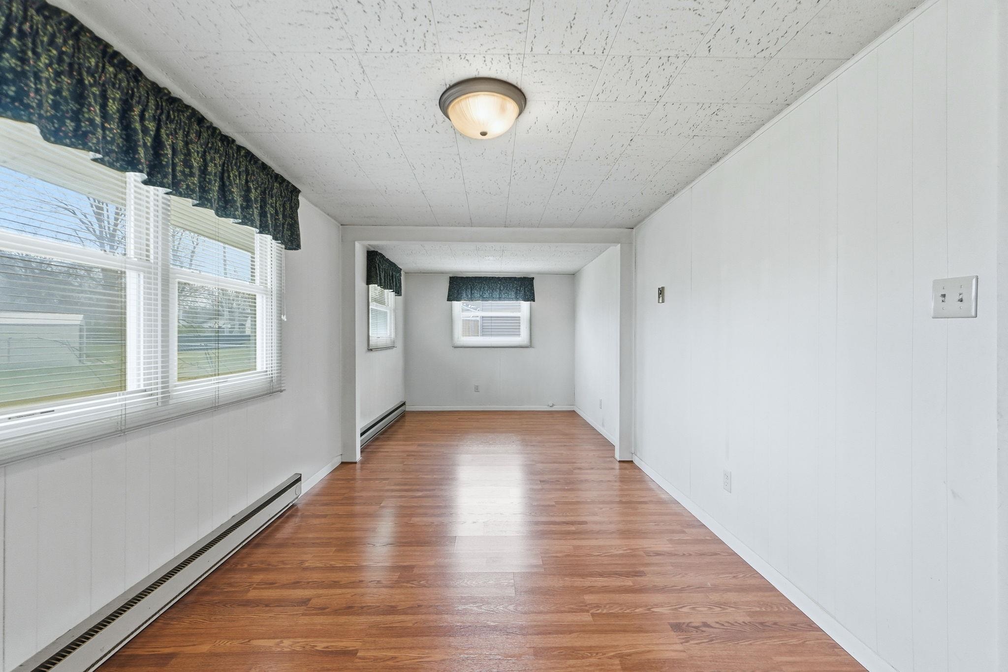 Spare room featuring a baseboard radiator, wood finished floors, baseboard heating, and wood walls
