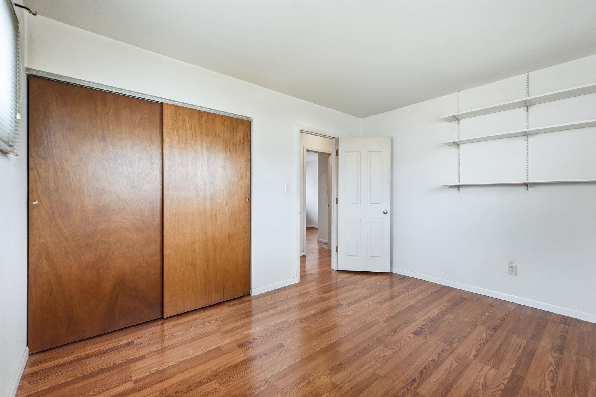 Unfurnished bedroom with wood finished floors and a closet