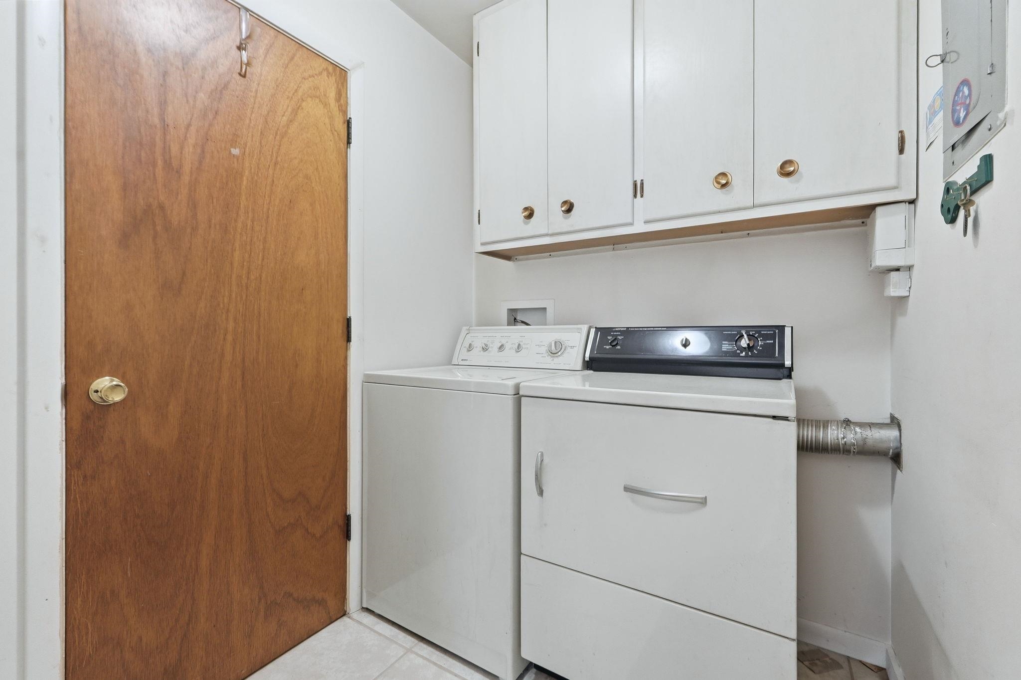 Laundry area featuring cabinet space, washing machine and clothes dryer, and light tile patterned floors