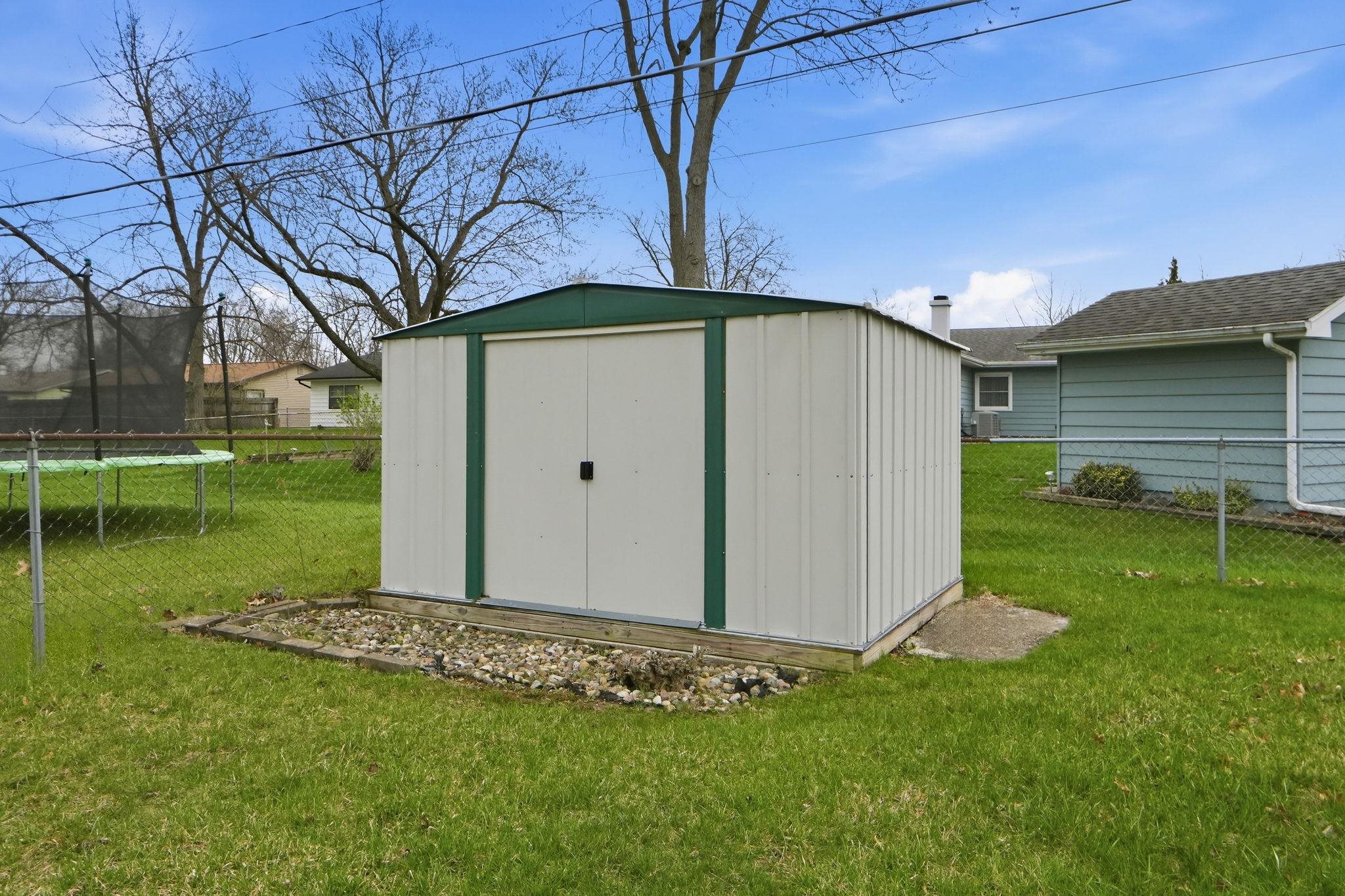 View of shed with a fenced backyard and a trampoline