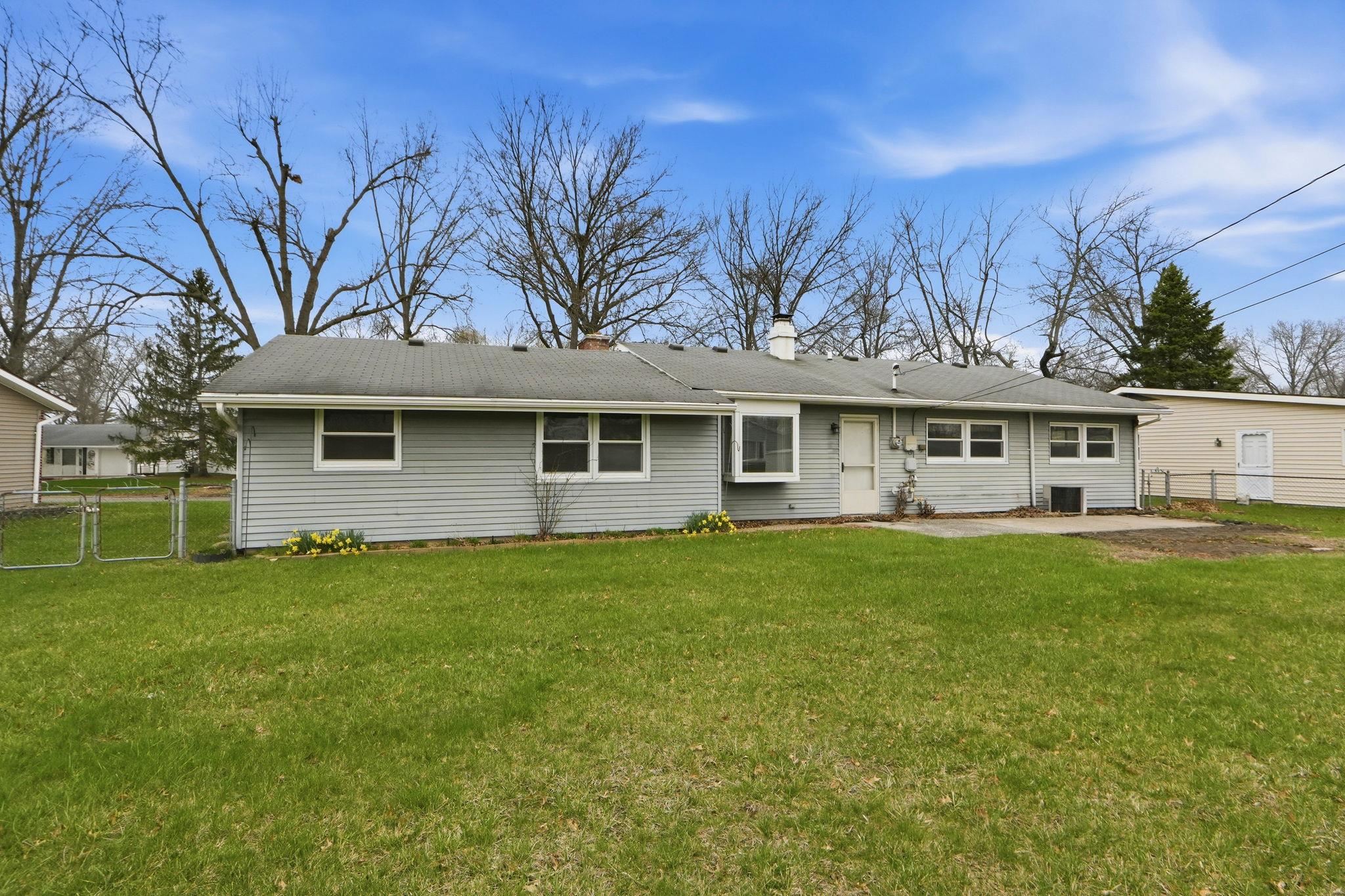 Rear view of house with a gate, a chimney, and a patio area