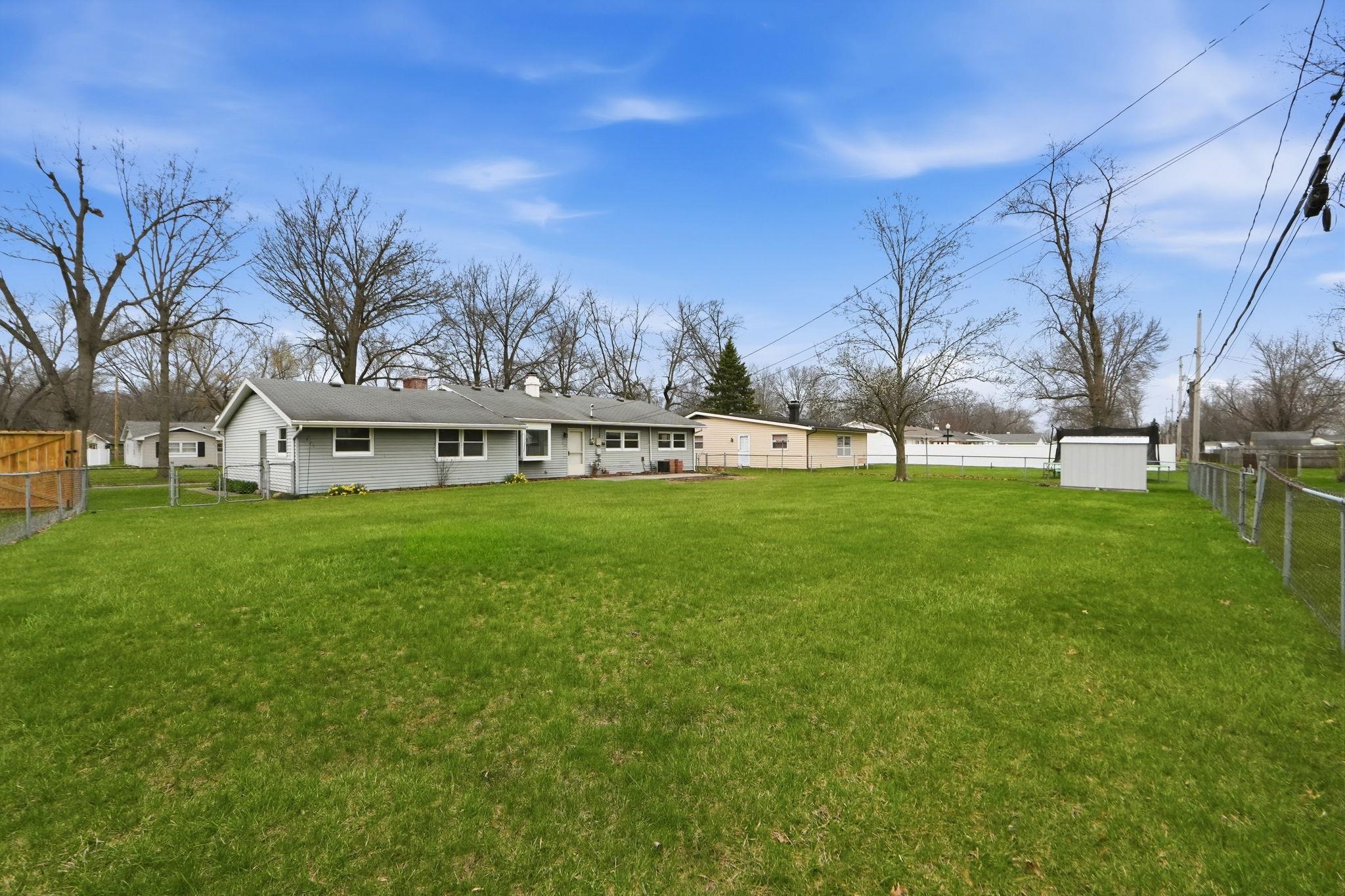 Back of property with a fenced backyard, a storage shed, and a chimney