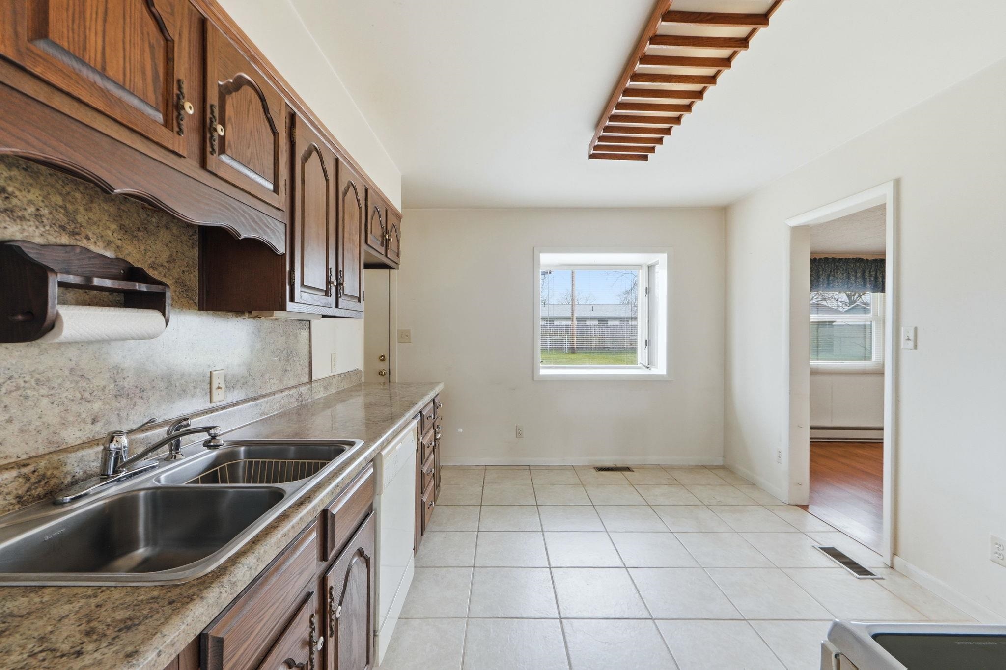 Kitchen featuring light tile patterned floors, plenty of natural light, white dishwasher, and decorative backsplash