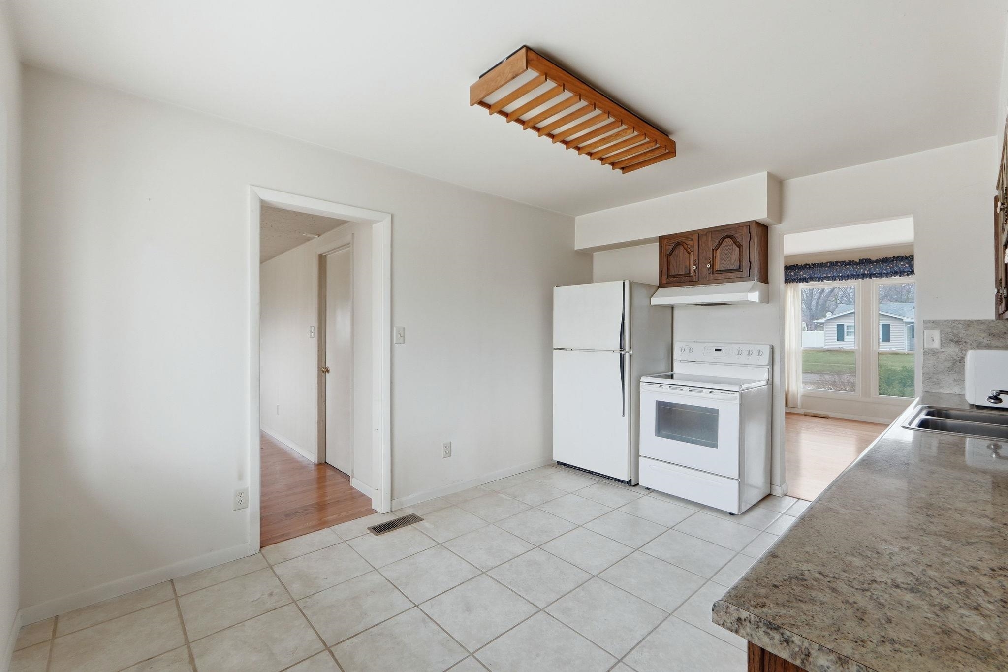Kitchen featuring white range with electric cooktop, light tile patterned flooring, and light countertops