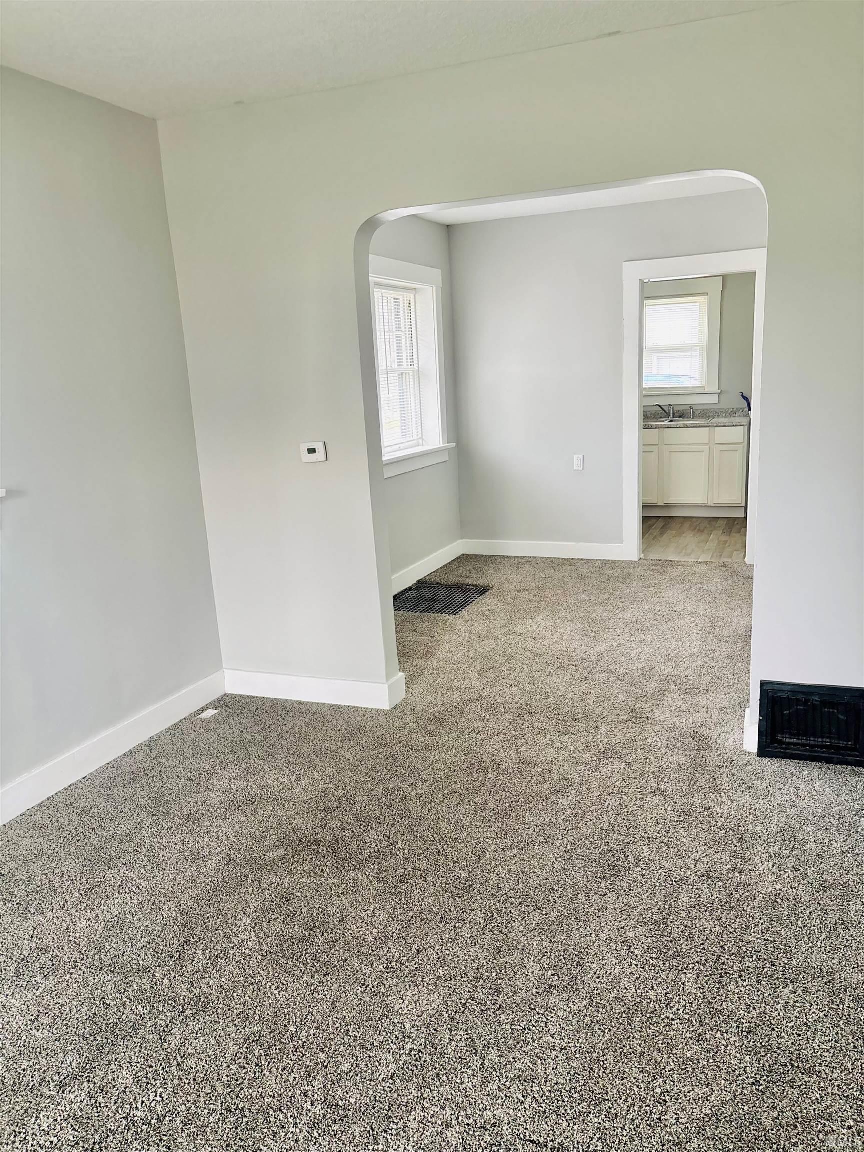 Spare room with arched walkways and light colored carpet