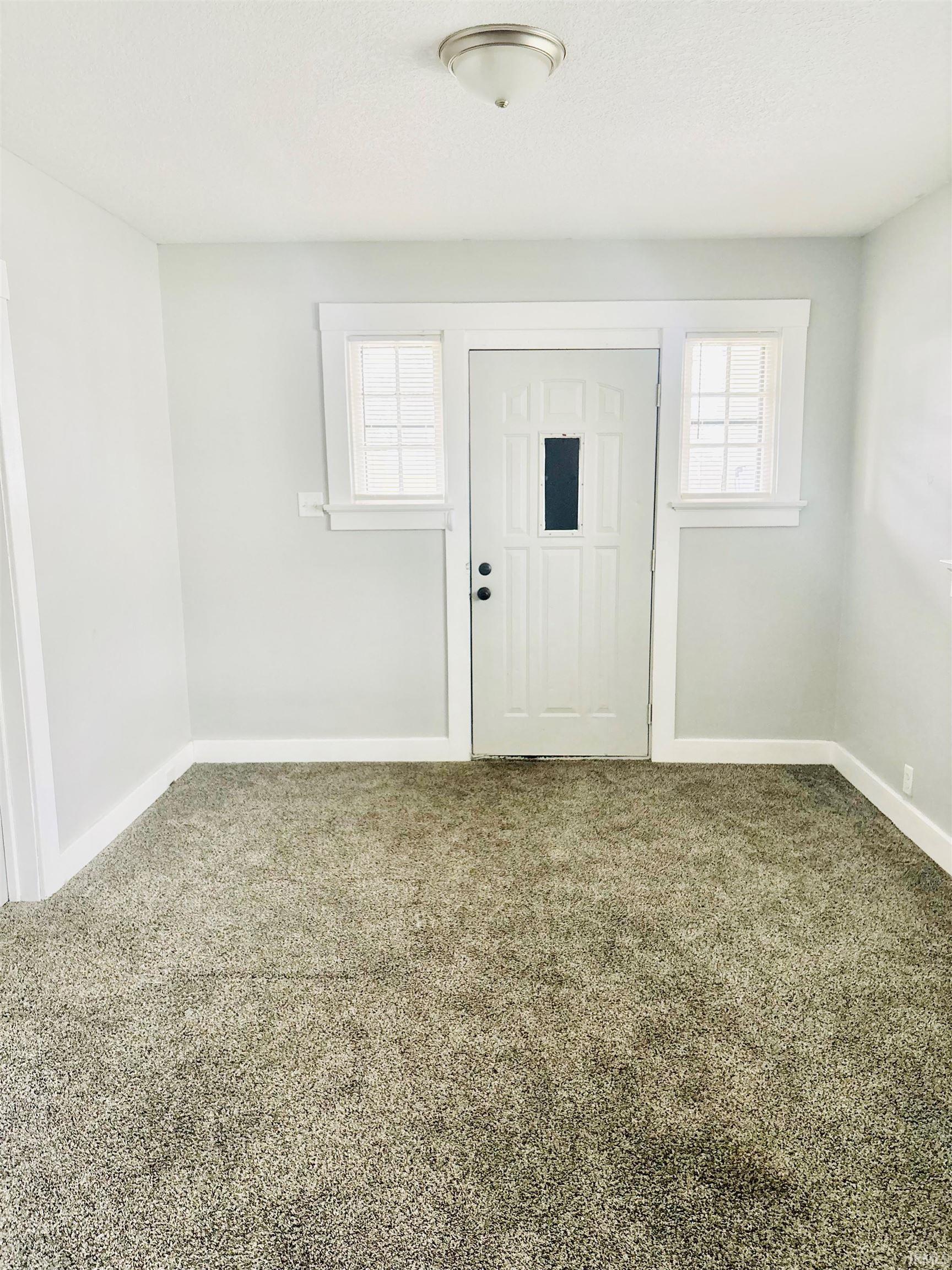 Carpeted entrance foyer featuring baseboards