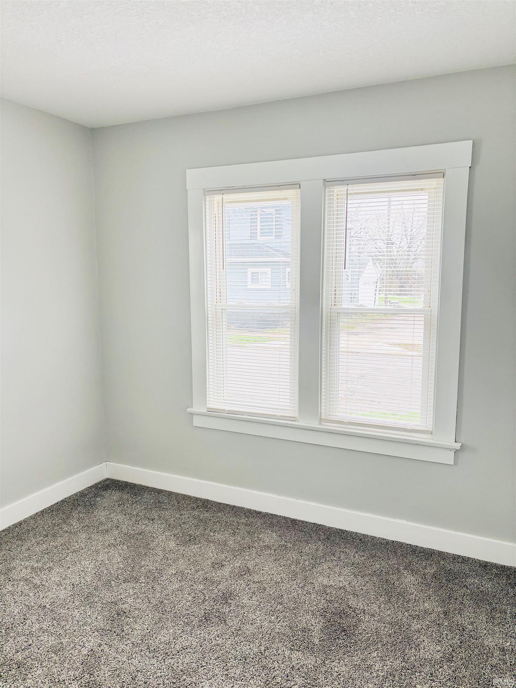 Empty room featuring baseboards and dark colored carpet