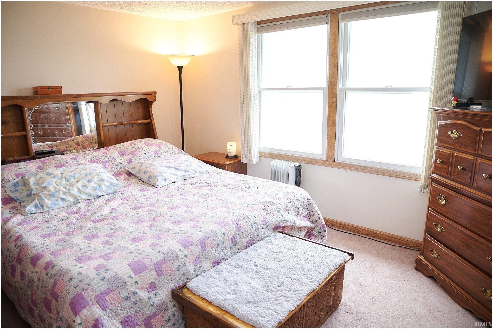 Bedroom with radiator heating unit, light carpet, and a textured ceiling