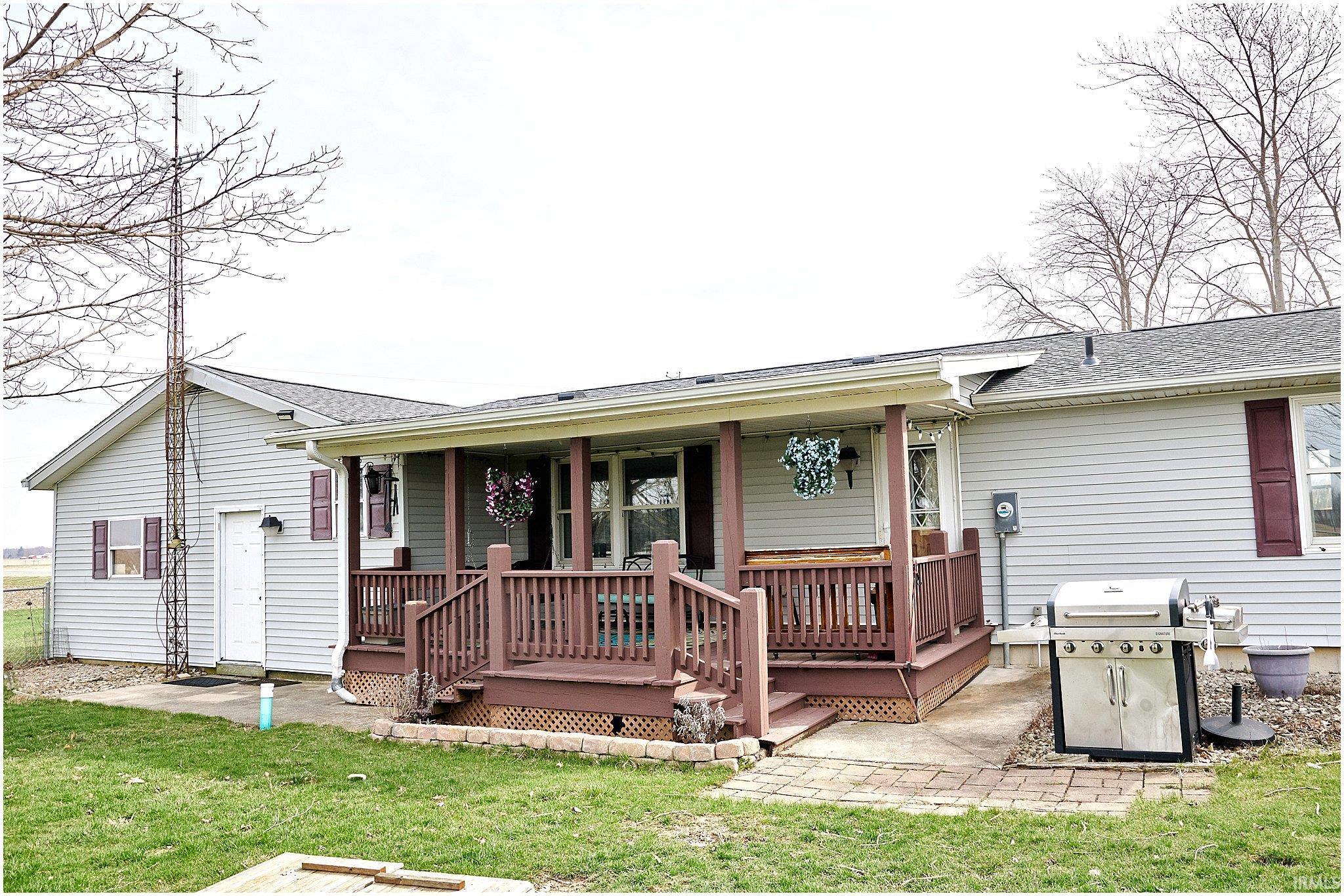Rear view of house with a shingled roof, a patio, a yard, and a wooden deck