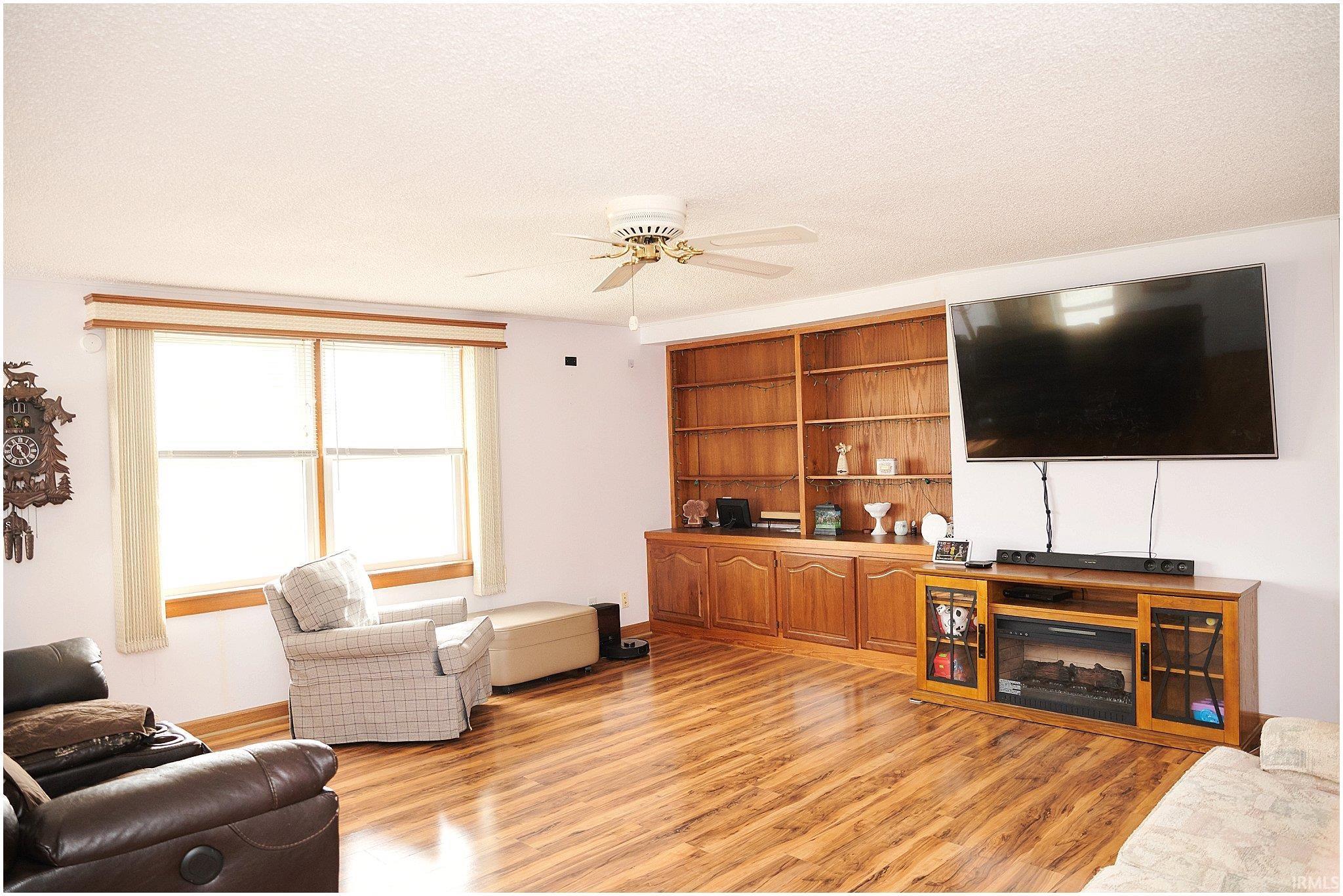 Living area with a ceiling fan, light wood-type flooring, and a textured ceiling