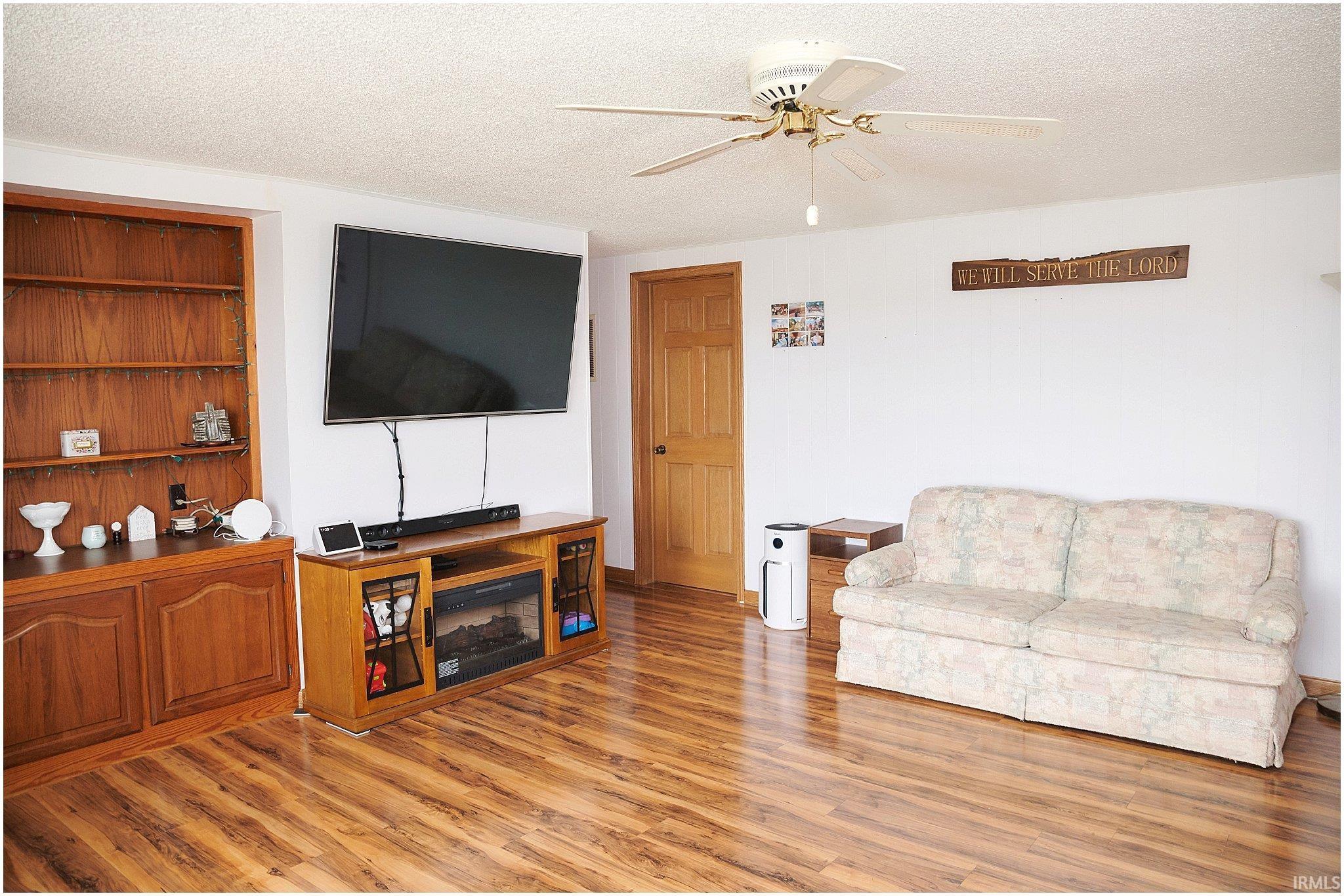 Living room featuring a textured ceiling, light wood finished floors, and ceiling fan