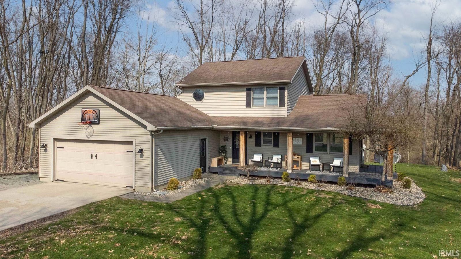 Traditional-style home with covered porch, roof with shingles, an attached garage, and concrete driveway