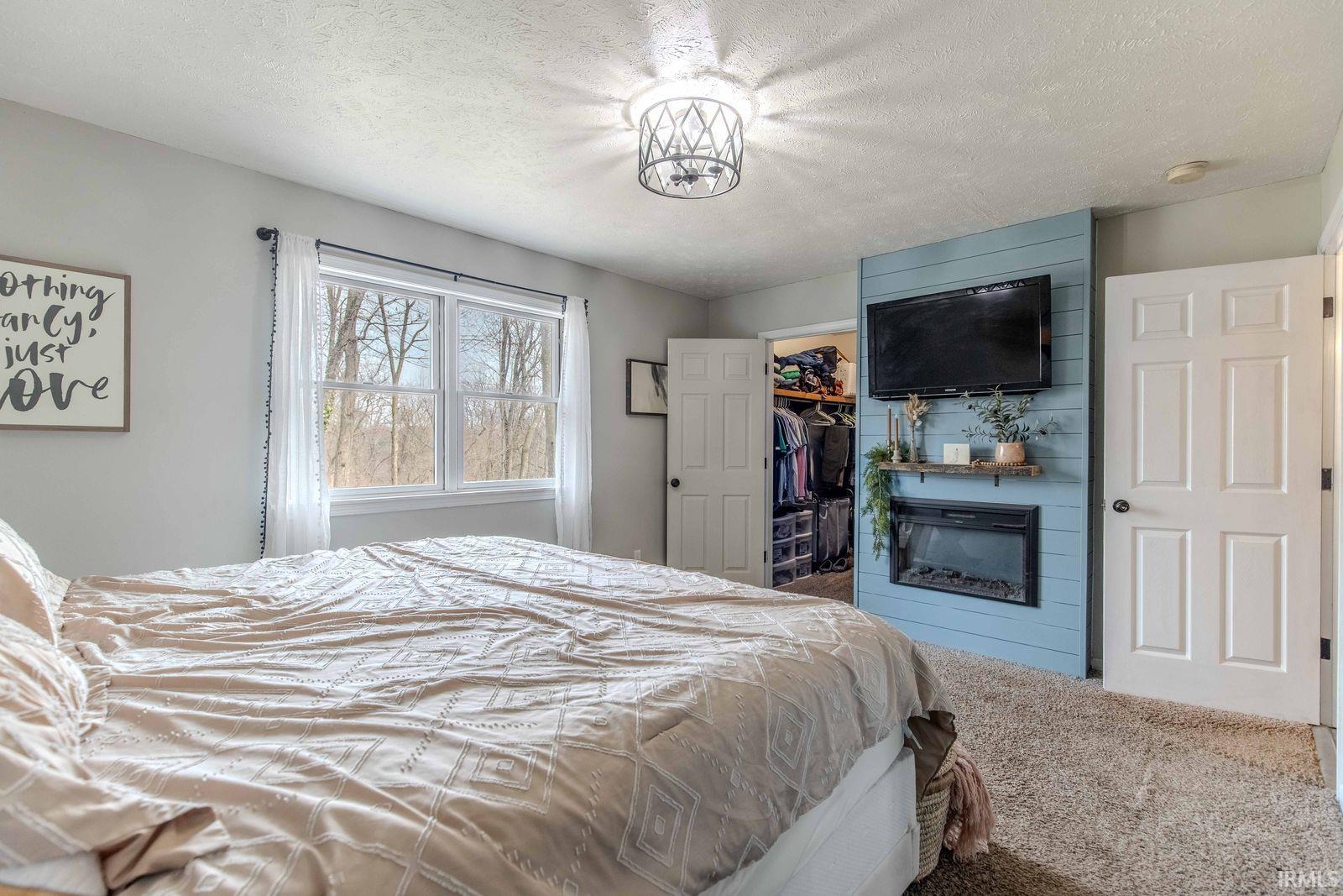 Bedroom with a textured ceiling, carpet, and a walk in closet