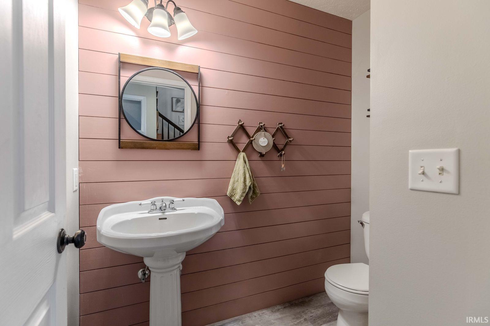 Half bathroom with toilet and wood walls