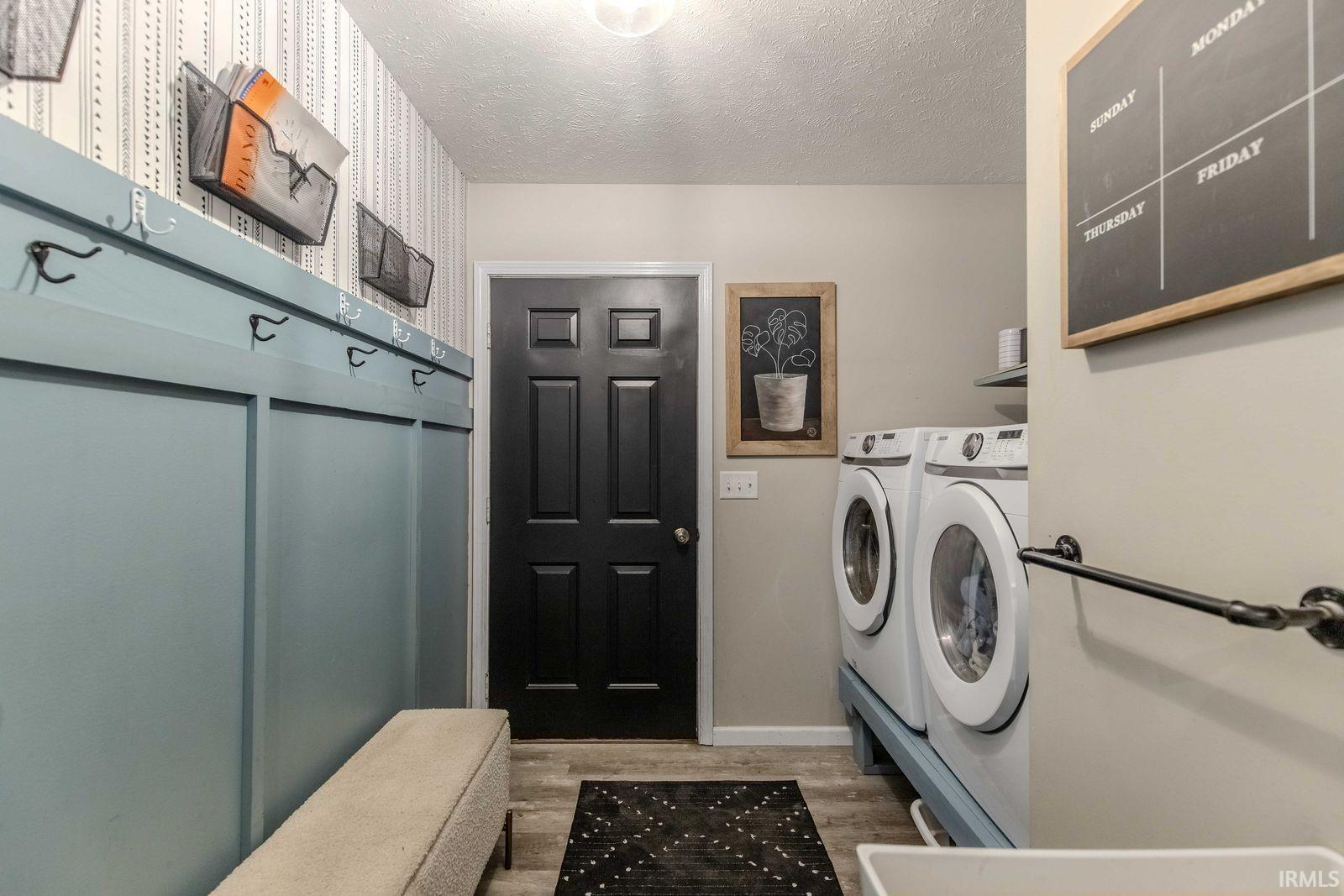 Laundry area featuring a textured ceiling, light wood-style flooring, and washer and dryer