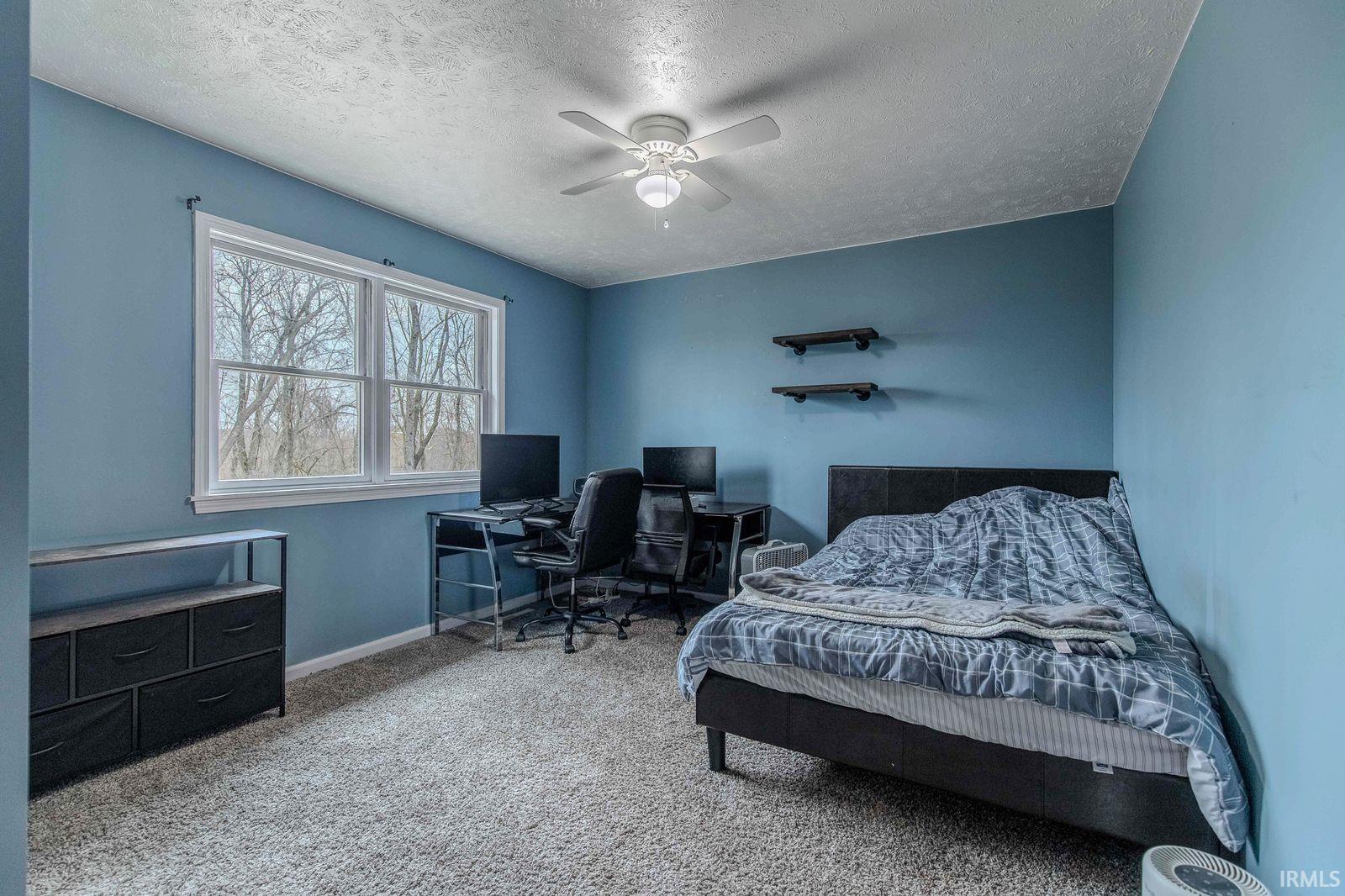 Bedroom with light carpet, a ceiling fan, a desk, and a textured ceiling