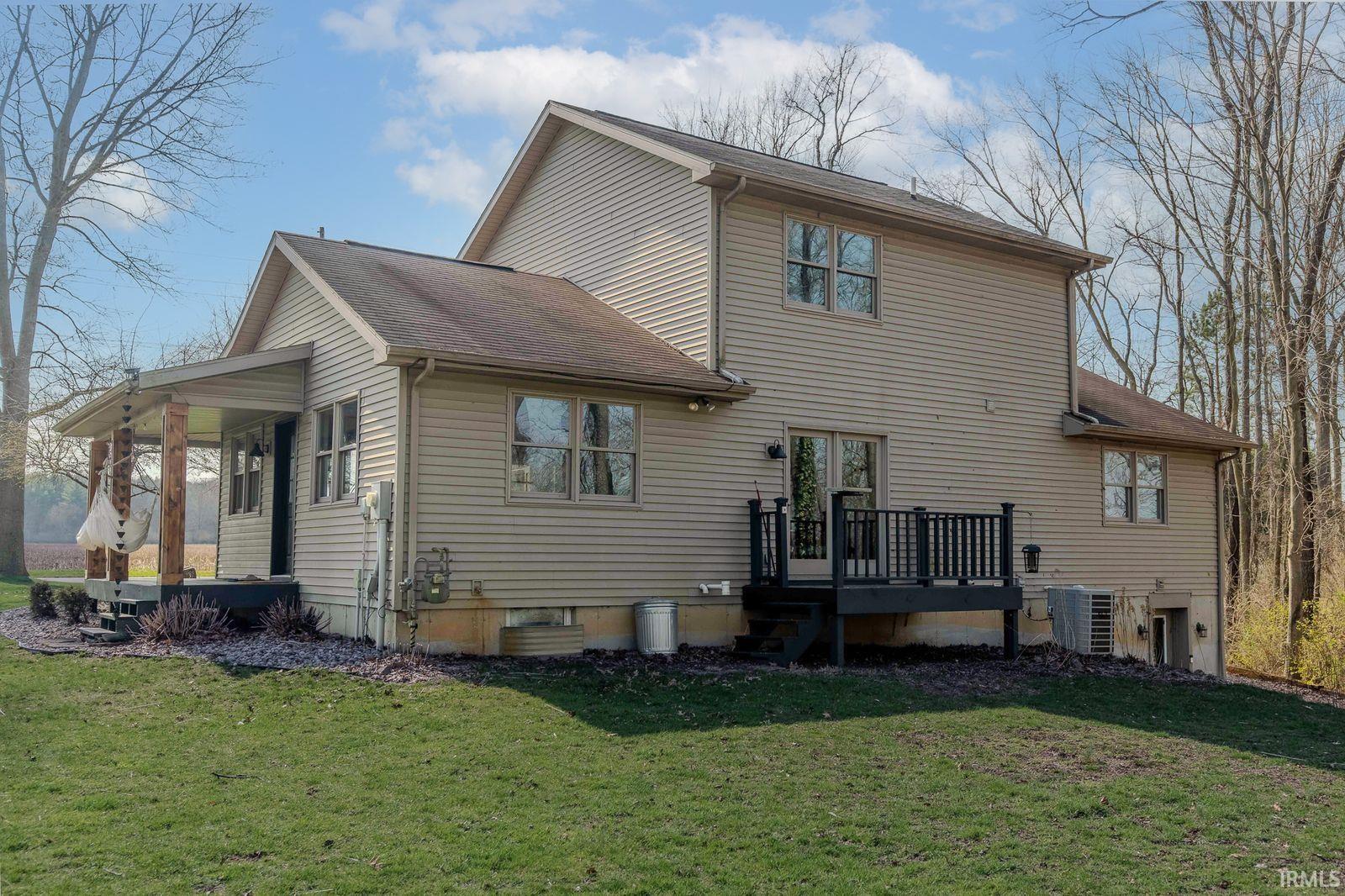 Rear view of house with a lawn, roof with shingles, and a wooden deck