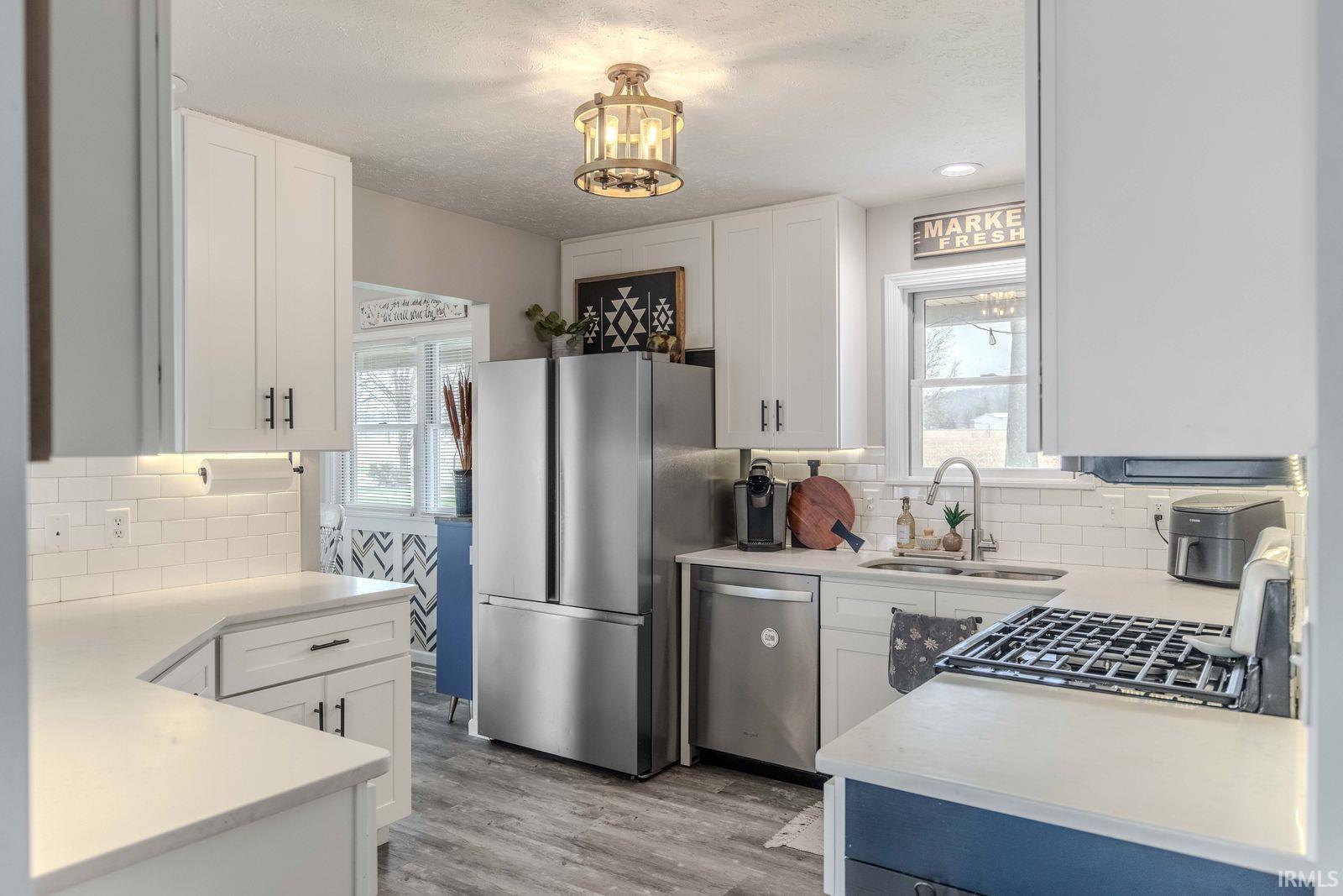 Kitchen with white cabinetry, stainless steel appliances, healthy amount of natural light, and light wood finished floors