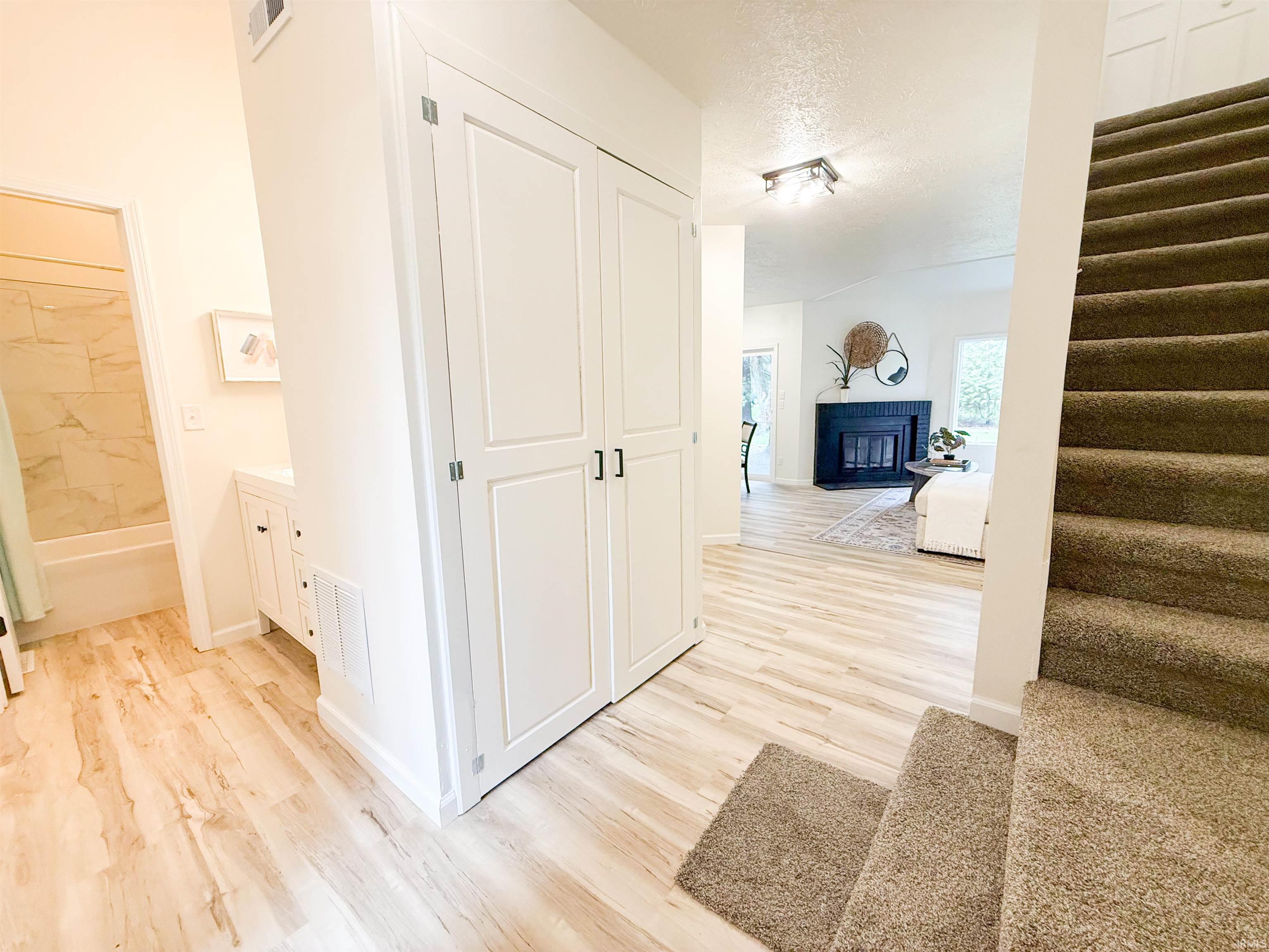Corridor with light wood finished floors and a textured ceiling