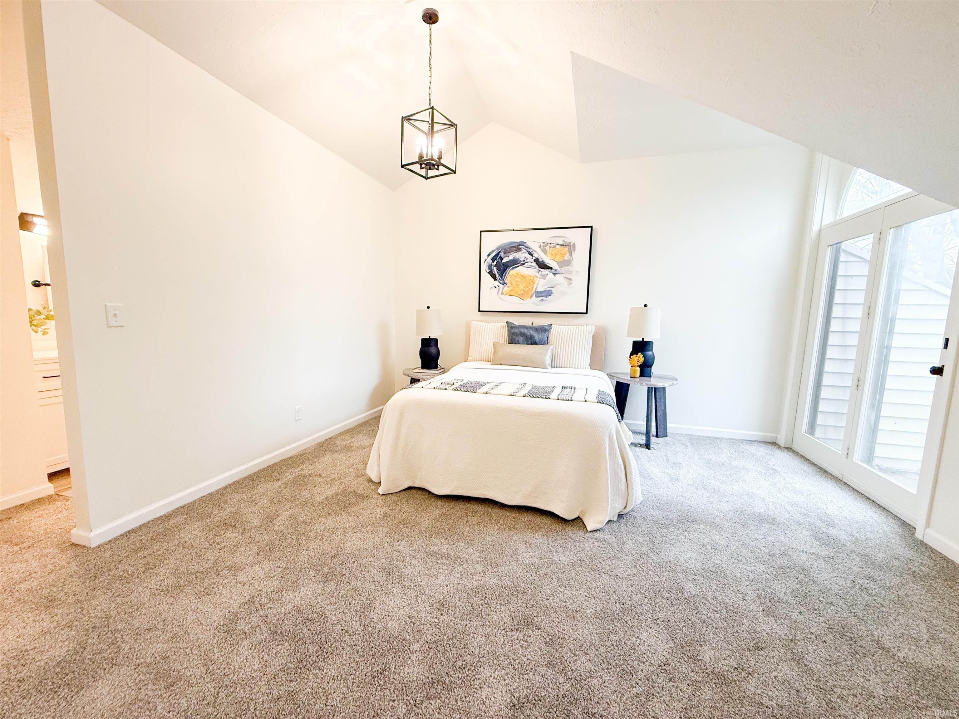 Bedroom featuring lofted ceiling and light carpet