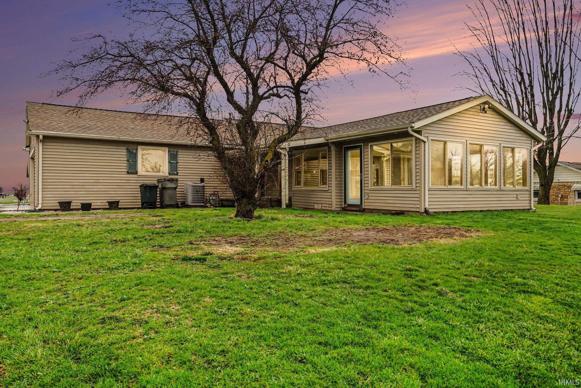 Rear view of house with a sunroom, a lawn, and a shingled roof