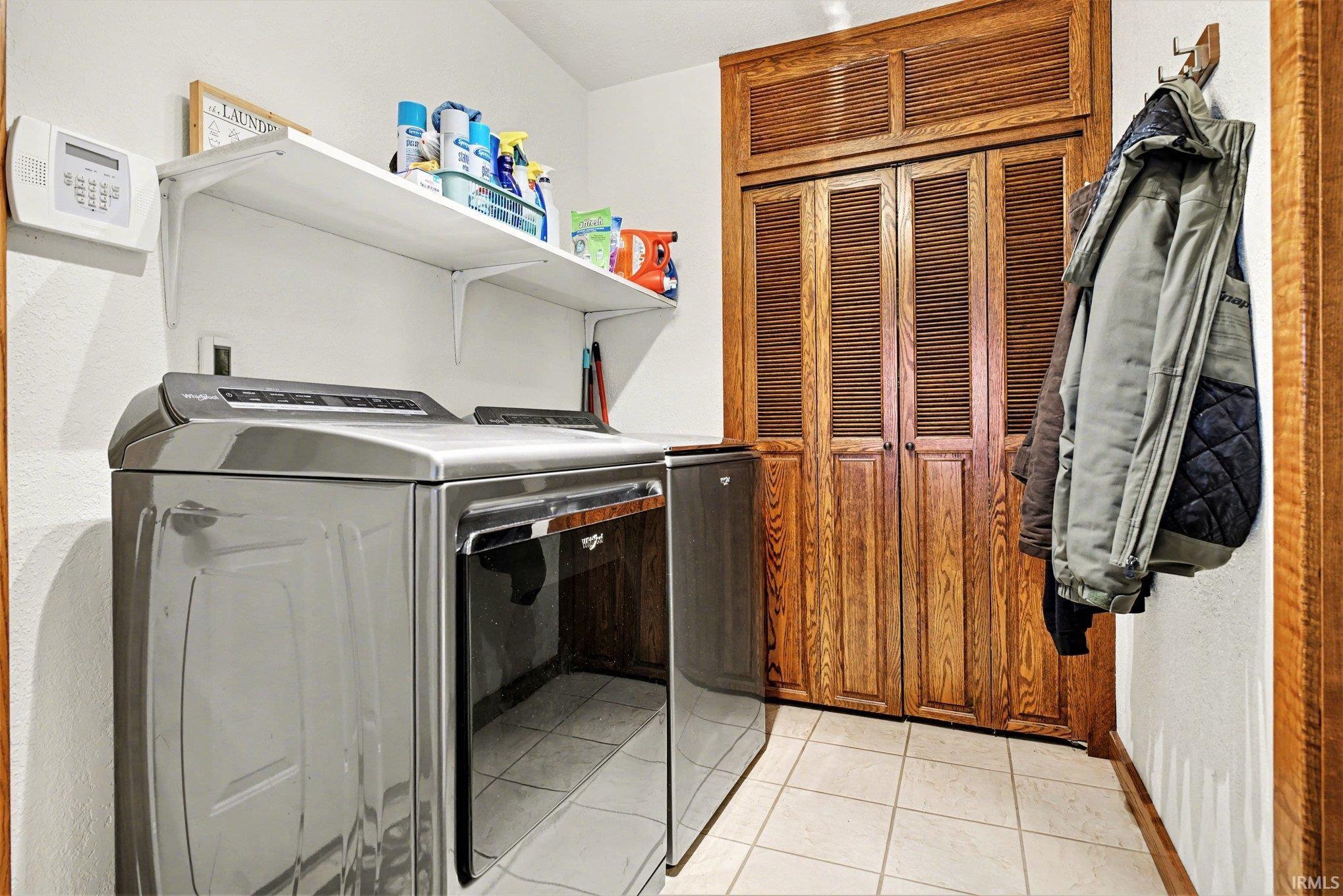 Laundry area with light tile patterned flooring and washing machine and clothes dryer