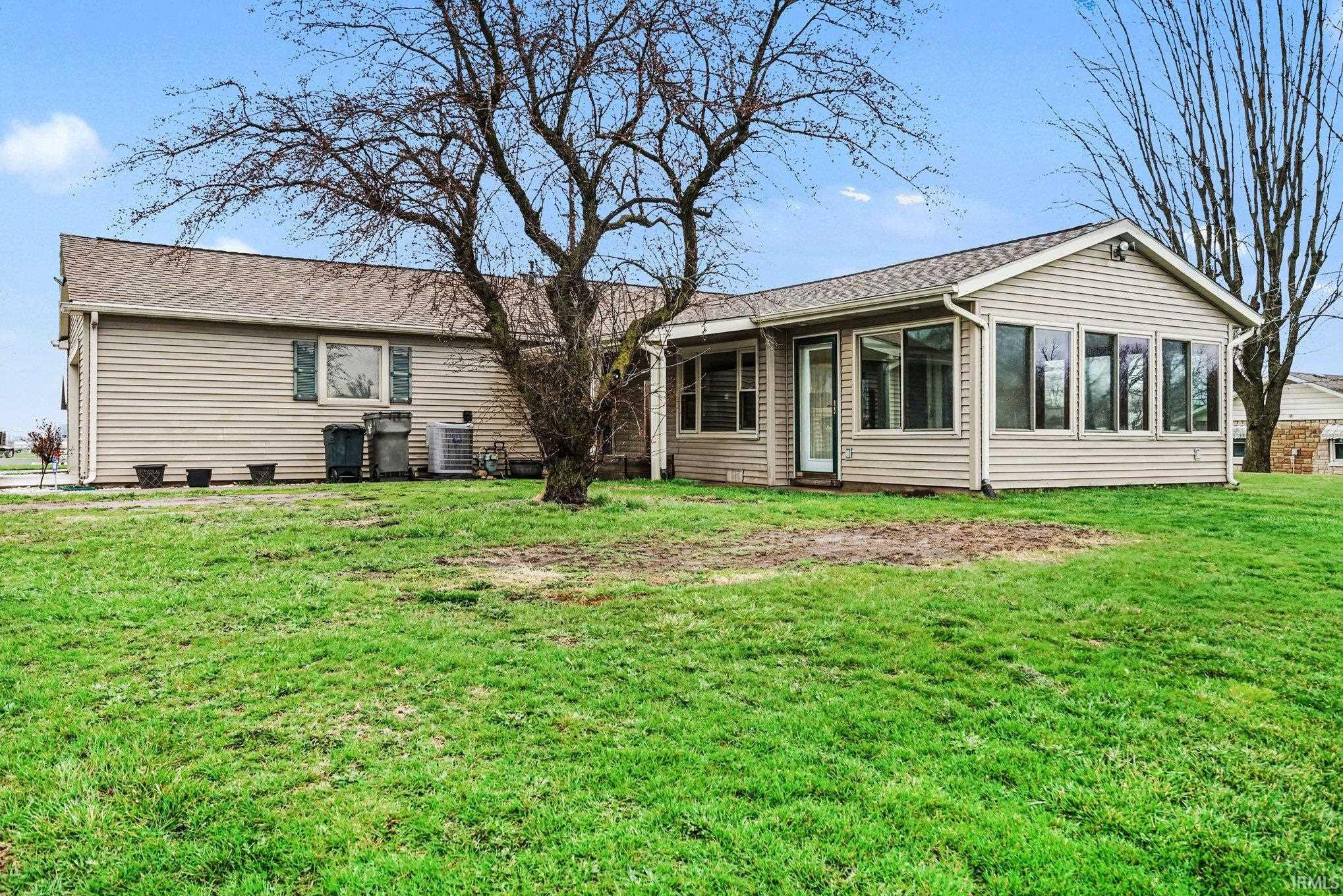 Rear view of property with a lawn, a sunroom, and a shingled roof