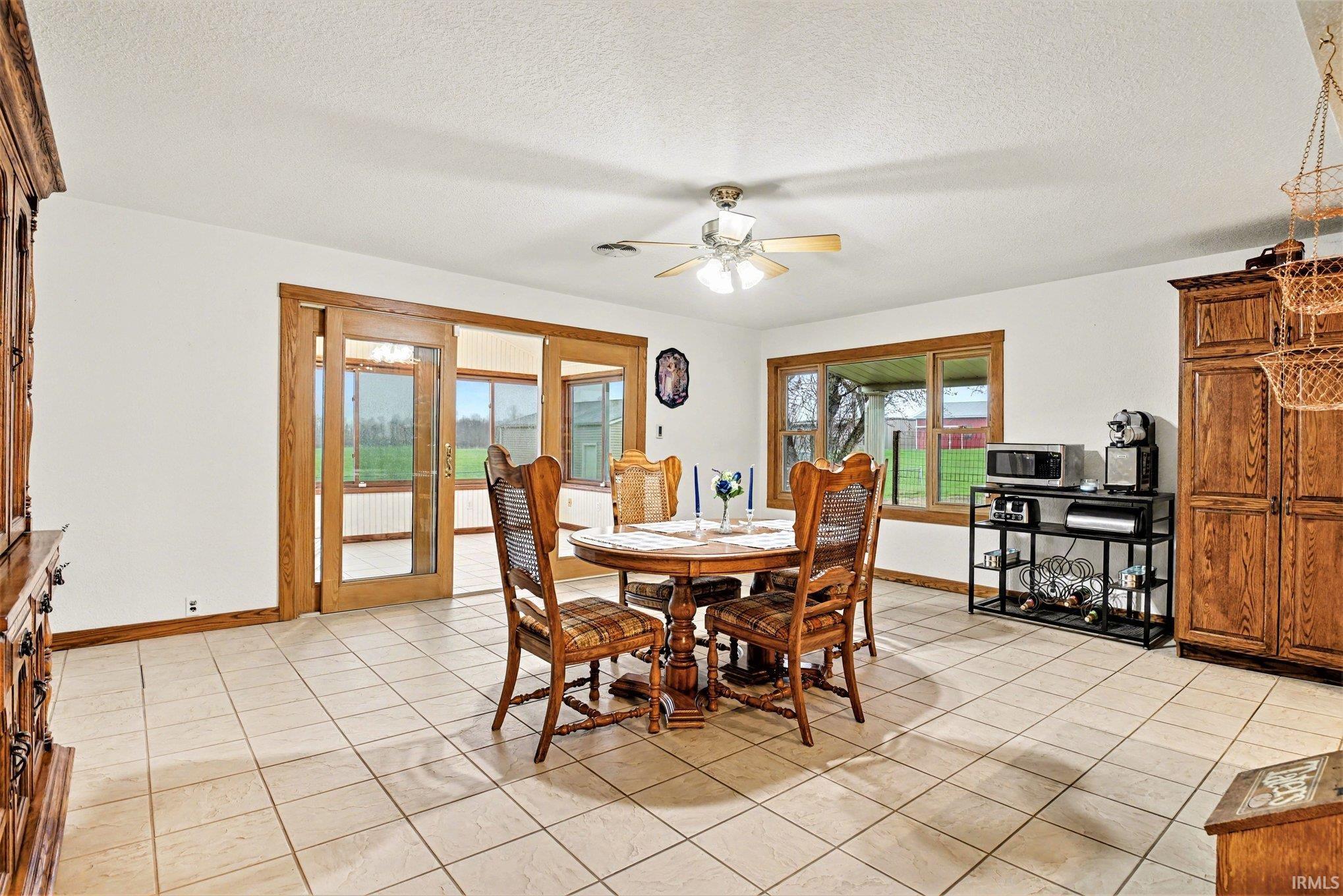 Dining space with a ceiling fan, a textured ceiling, and light tile patterned flooring