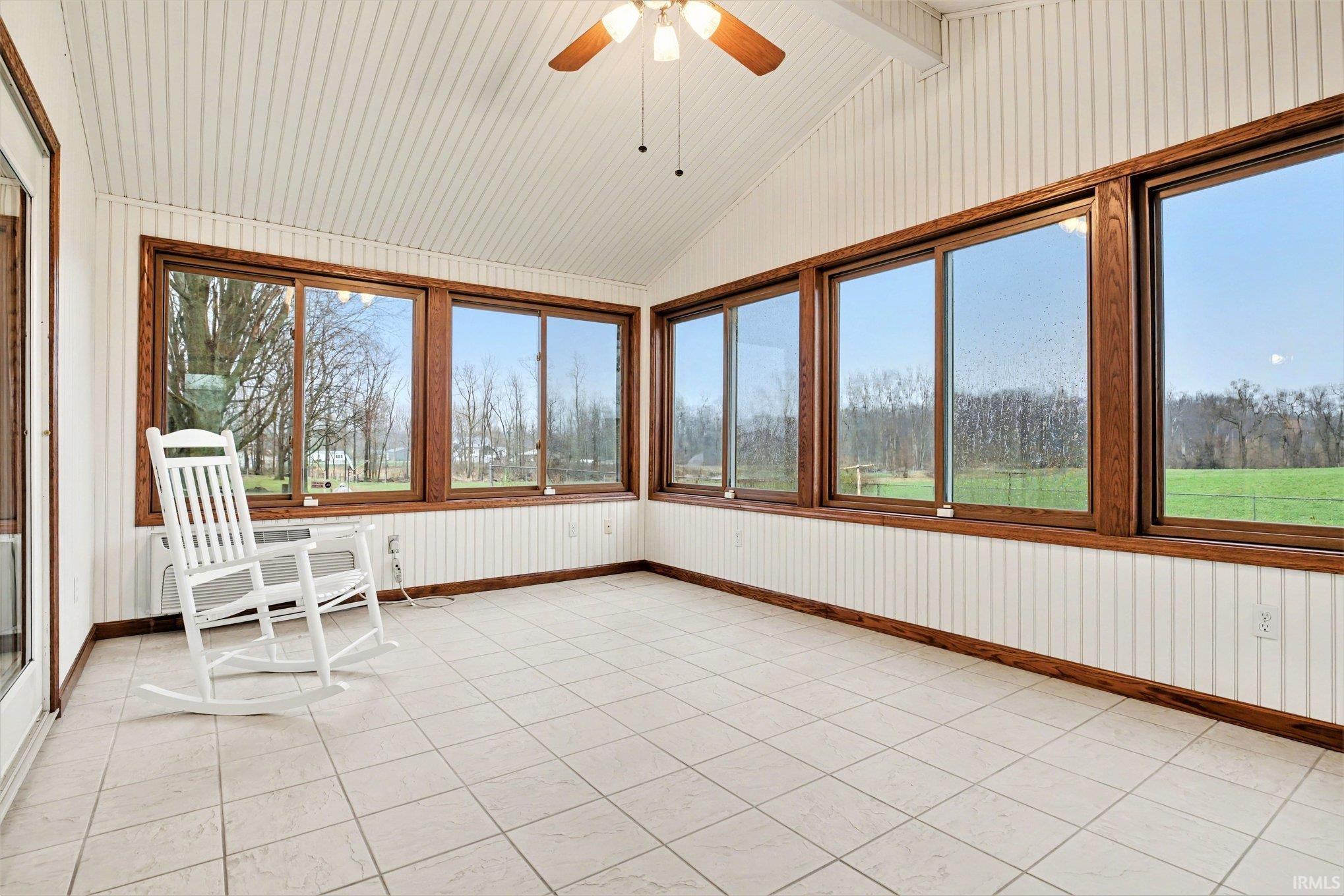 Unfurnished sunroom featuring a wall mounted air conditioner and beam ceiling